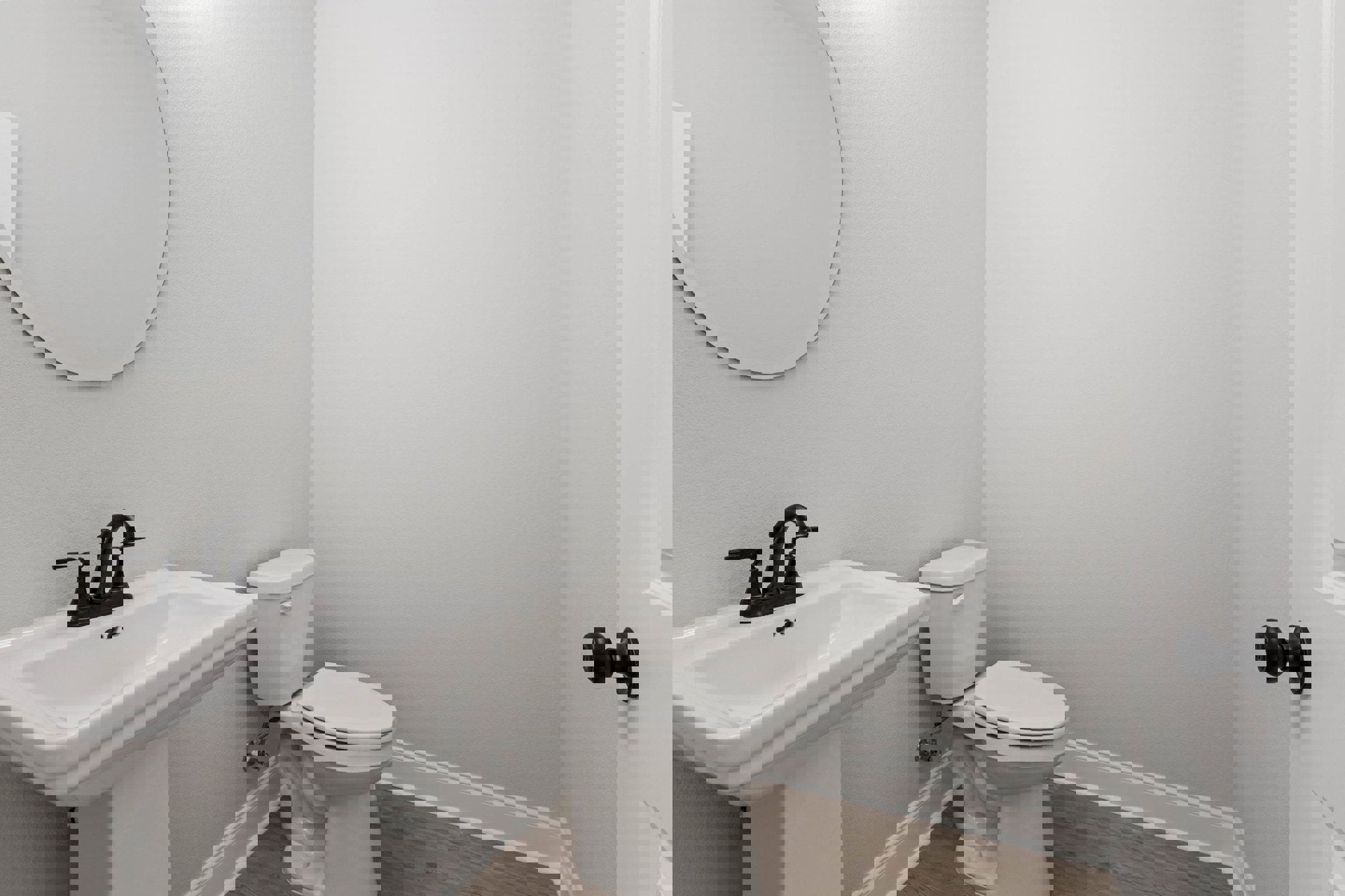 White bathroom with round mirror above white sink, black faucet, white toilet, light tile walls, and chrome doorknob