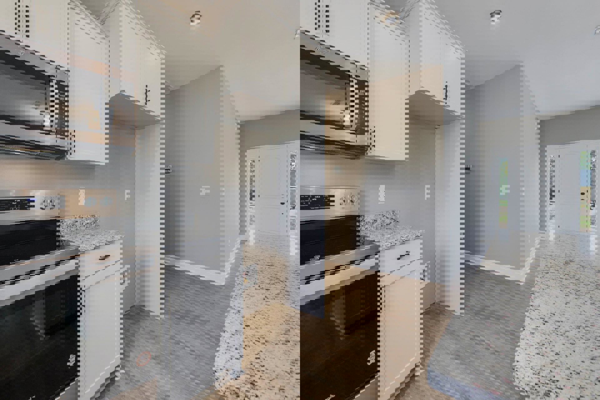 Marble countertop kitchen with built-in microwave, white cabinetry, glass-paneled door, and overhead lighting