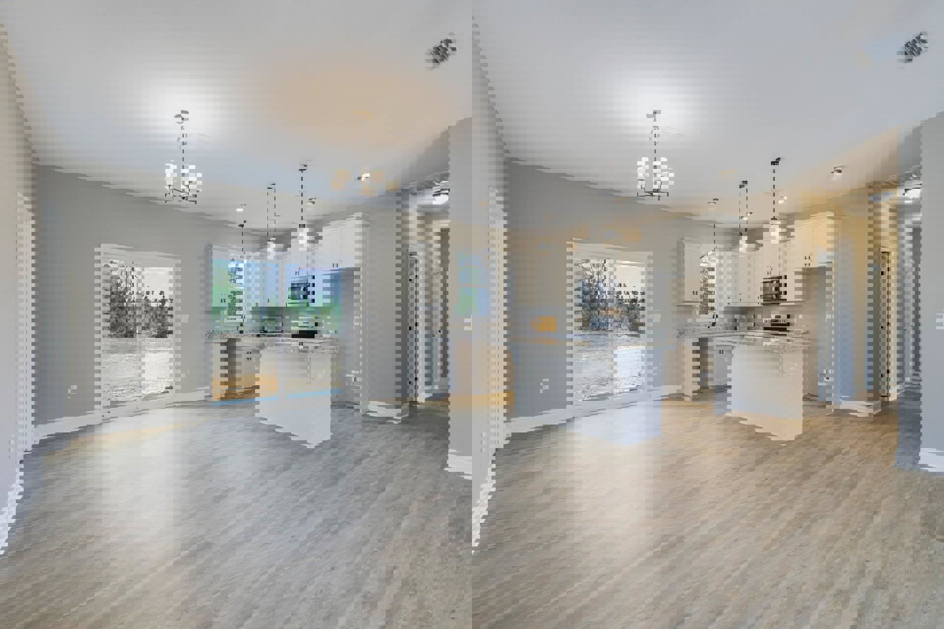 Open kitchen and dining area featuring wood flooring, white walls, a white kitchen island with built-in TV, cabinetry, microwave oven, sliding glass door, and window overlooking