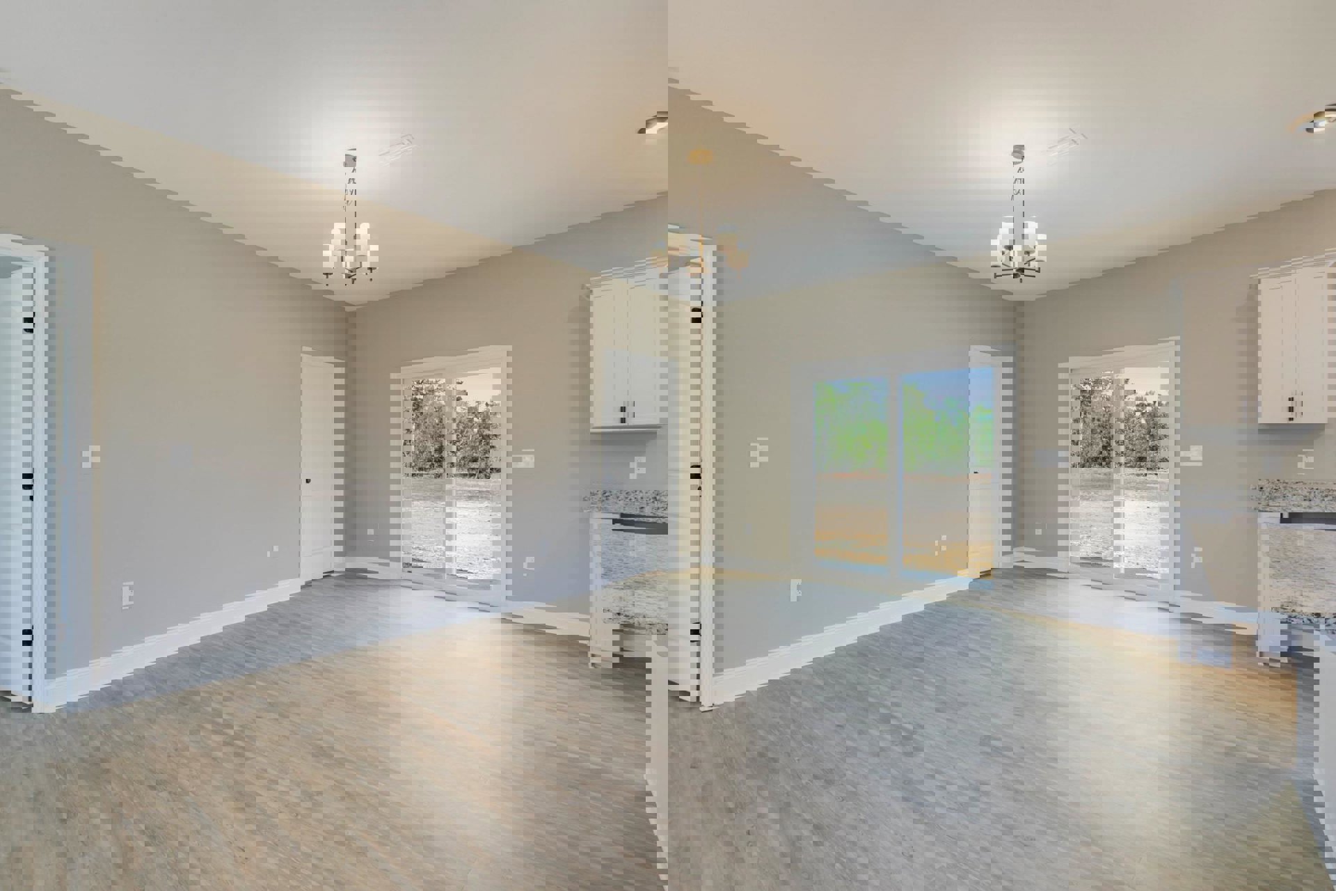 Hardwood floor room featuring a white door with black knob, sliding glass door, white cabinet, and modern chandelier against light plaster walls