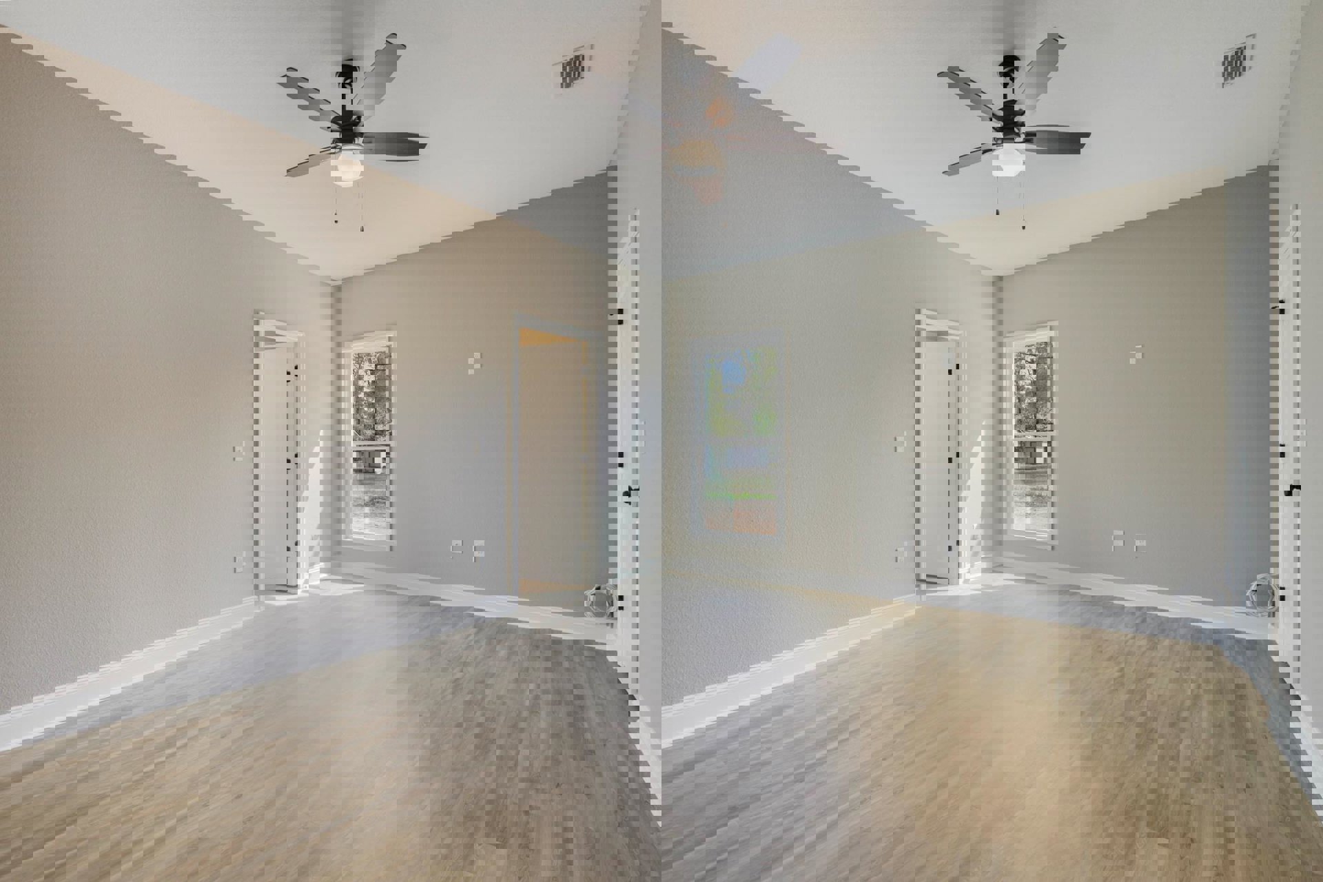 White room with wood flooring, ceiling fan with light, open white door with black handle, window showing shed outside, wall vent, plaster walls with molding