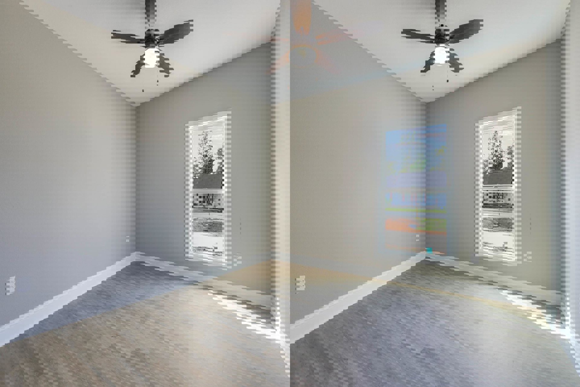 Wood flooring room with white plaster walls, ceiling fan with light fixture, large window, and visible electrical outlet