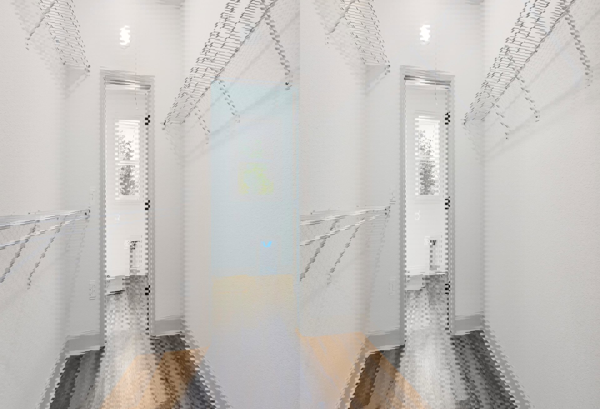 Hallway with white plaster walls, wood flooring, metal shelving, circular ceiling light, window showing trees, and white door with glass panel