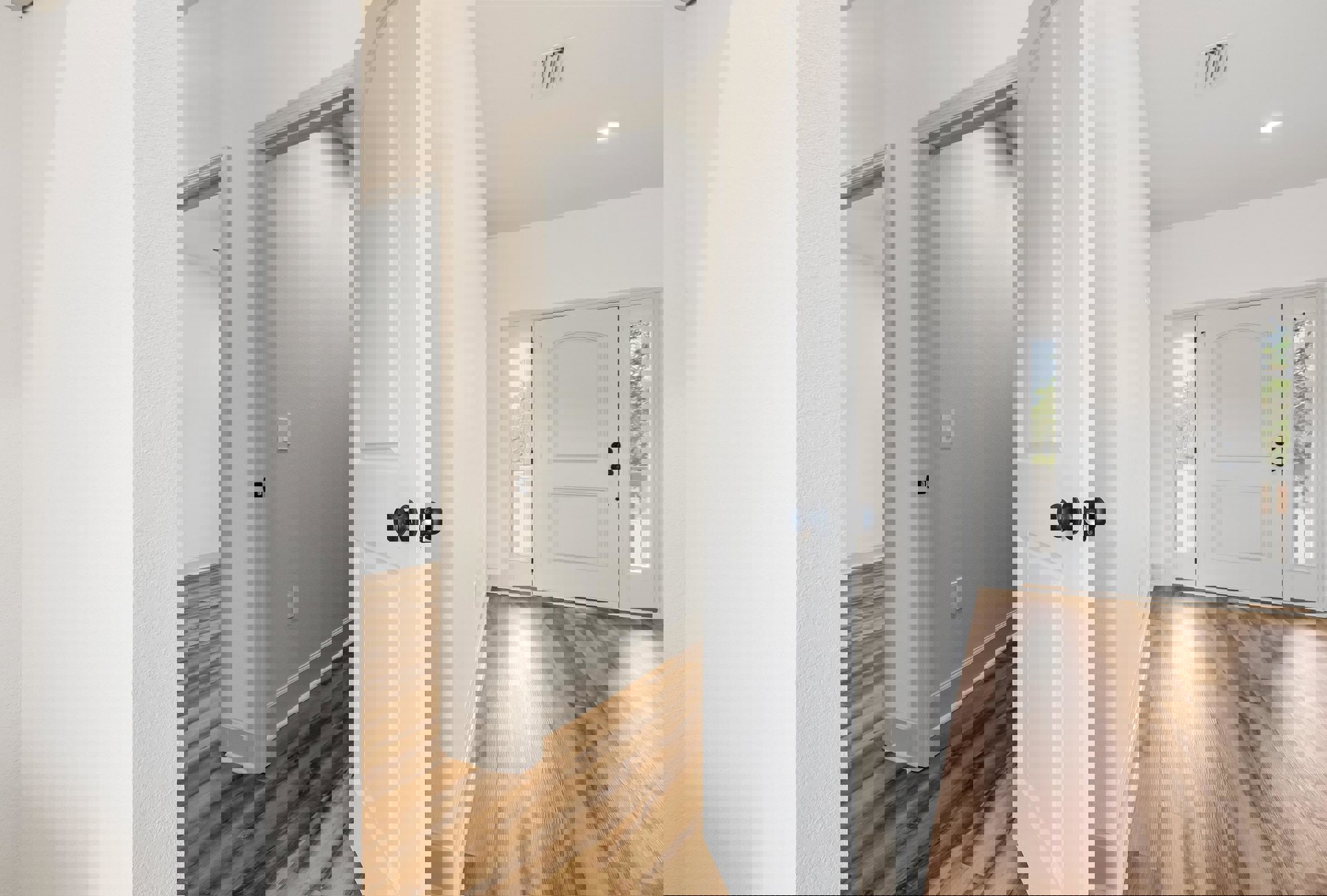 White paneled door with glass windows, brushed metal door knob, wood flooring with white baseboard trim, wall-mounted light switch and air vent, neutral painted walls