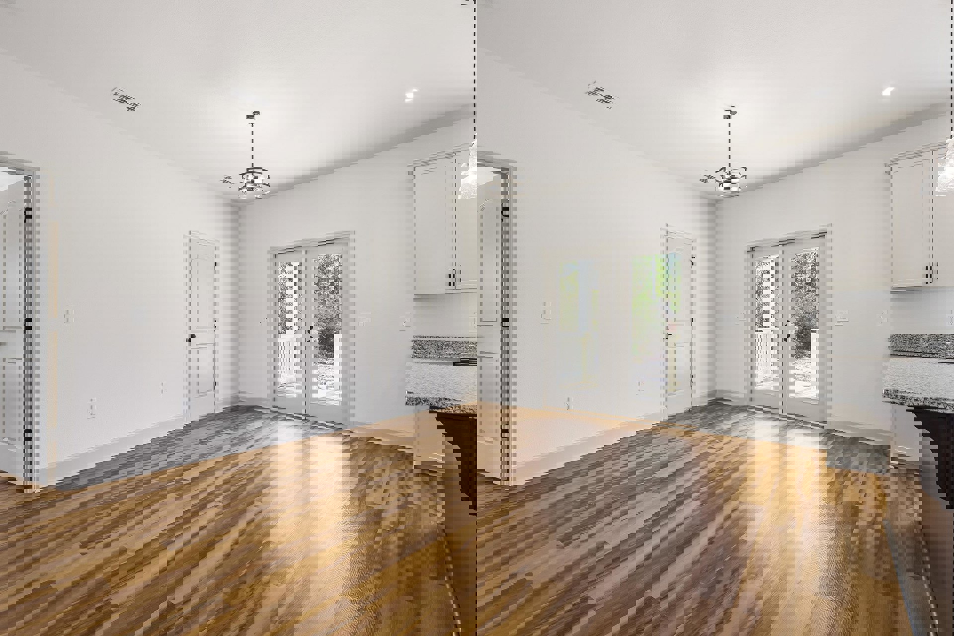 Hardwood floor and white walls in a bright room, featuring double glass-paneled doors, a white door with black hardware, and a modern chandelier