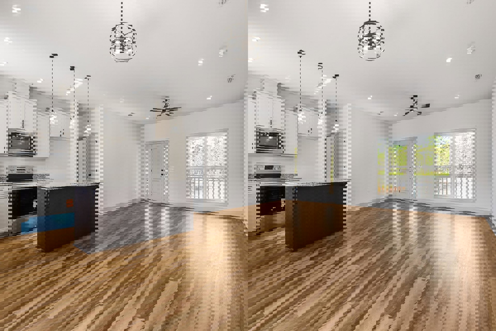 Open kitchen with hardwood flooring, marble-topped island, white cabinetry, built-in microwave, glass-paneled door, and large window overlooking deck and trees.