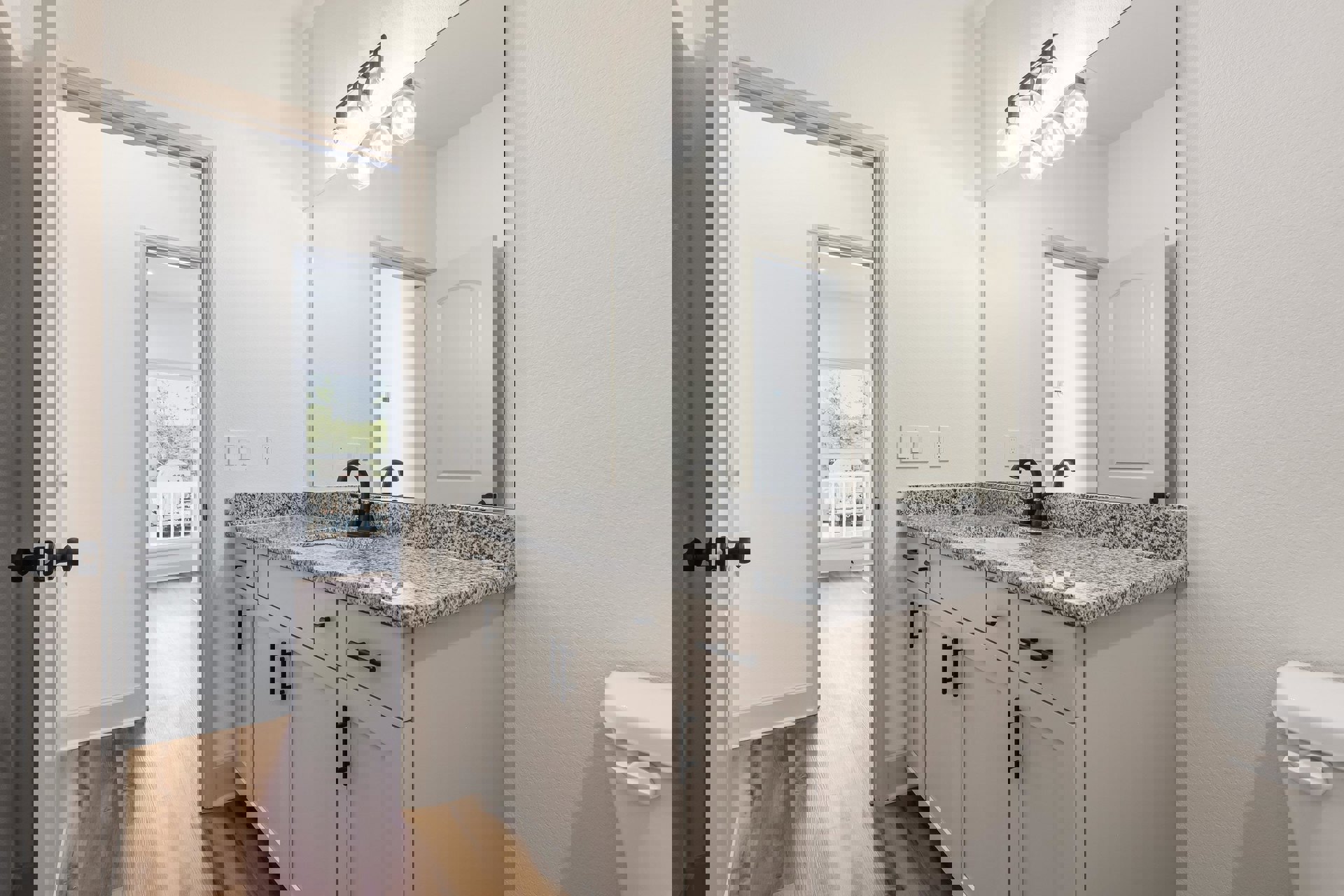 Marble countertop with undermount sink, chrome faucet, large framed mirror, white cabinetry, black hardware, and multi-bulb light fixture in a modern bathroom