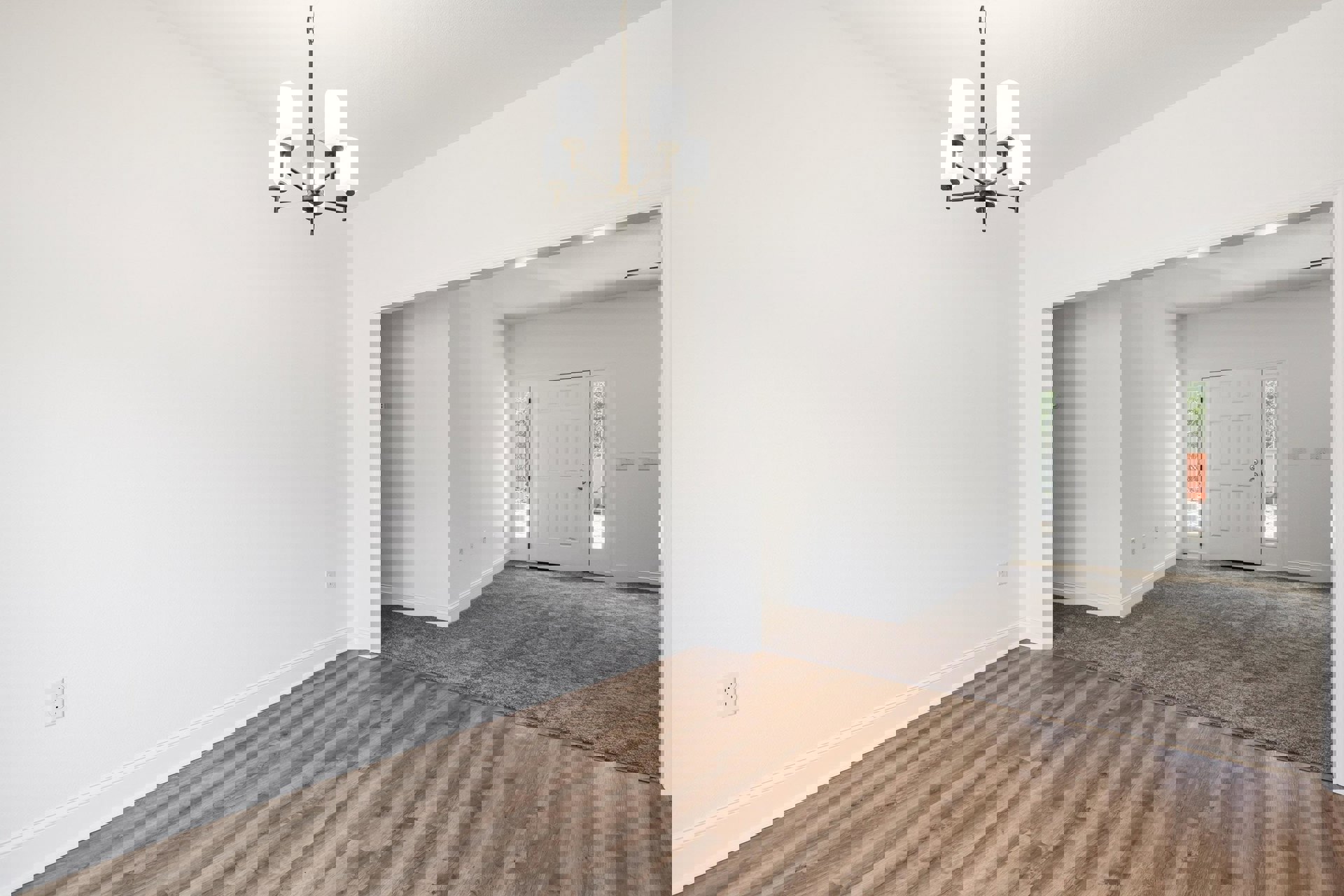 Wood floor room with white paneled walls, silver-knobbed white door, and multi-arm chandelier with white lampshades hanging from plaster ceiling.