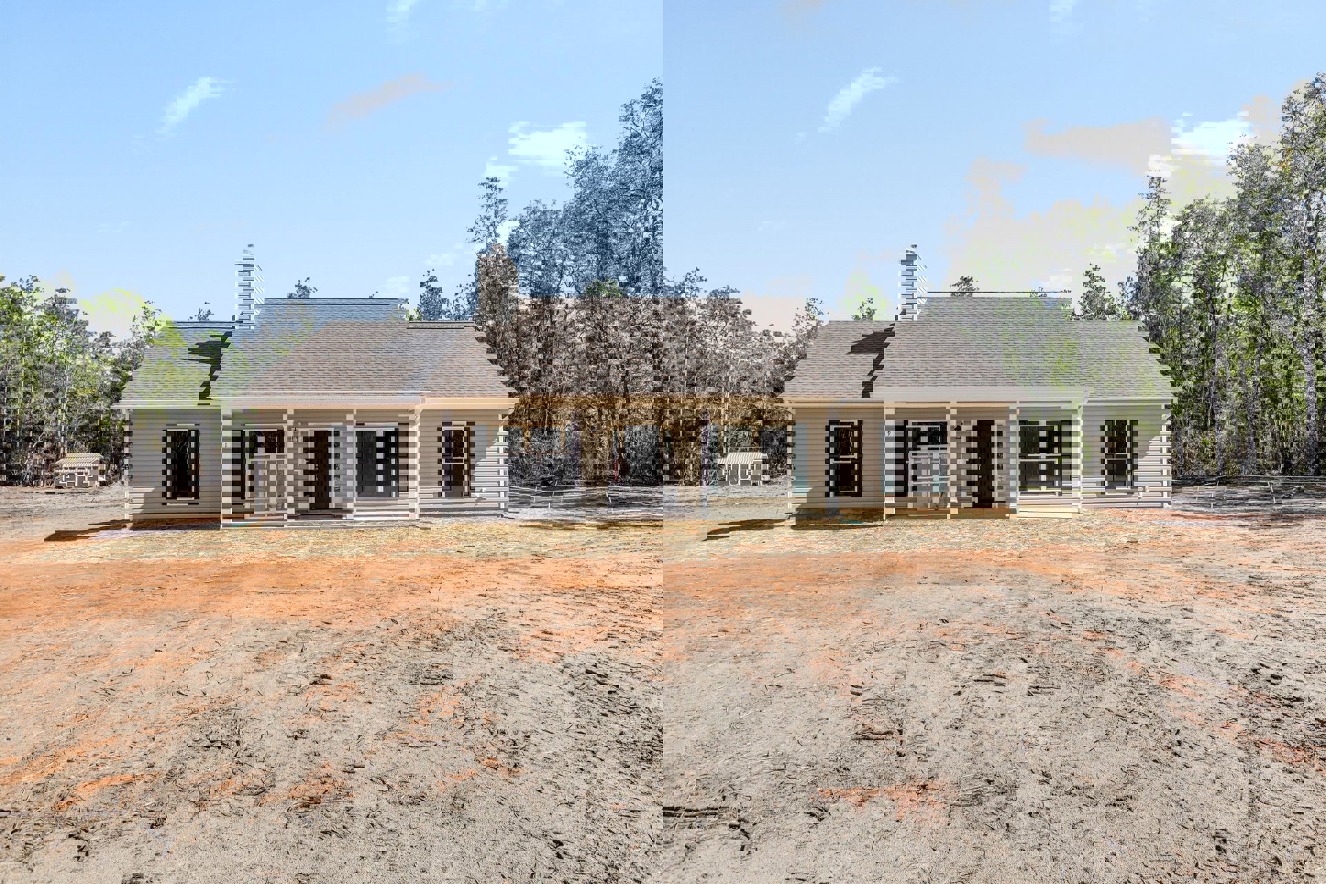 Modern house exterior with black glass-panel door, white-framed window, brick chimney, and dirt yard scattered with sticks