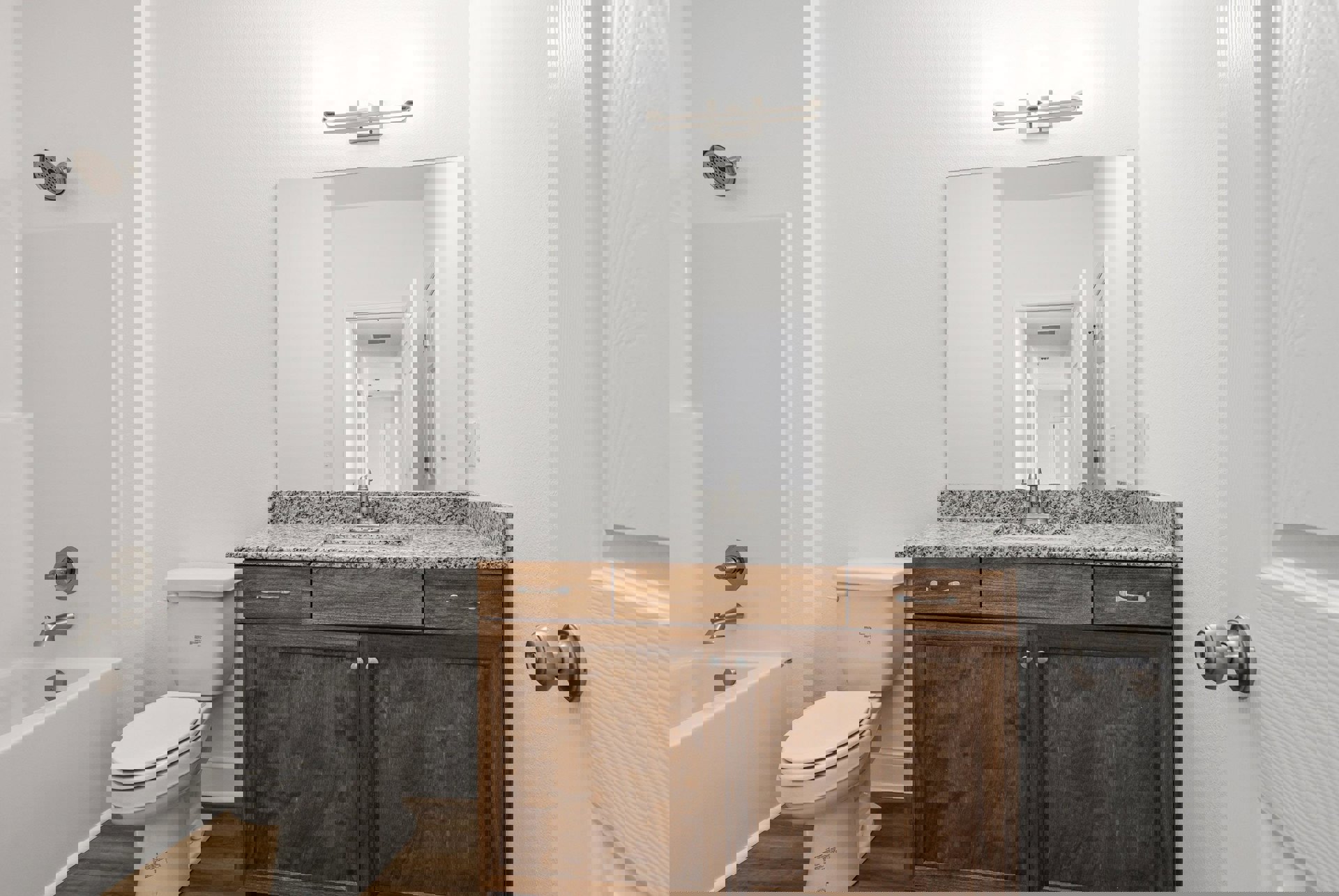 Marble countertop with undermount sink, chrome faucet, white toilet, and partial view of white bathtub against tiled walls