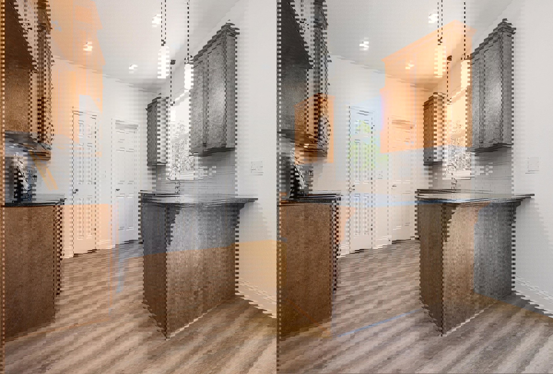 Kitchen with natural wood cabinets and matching wood floor, wooden countertop with built-in sink, overhead ceiling light, white door with silver knob, row of wall switches, and