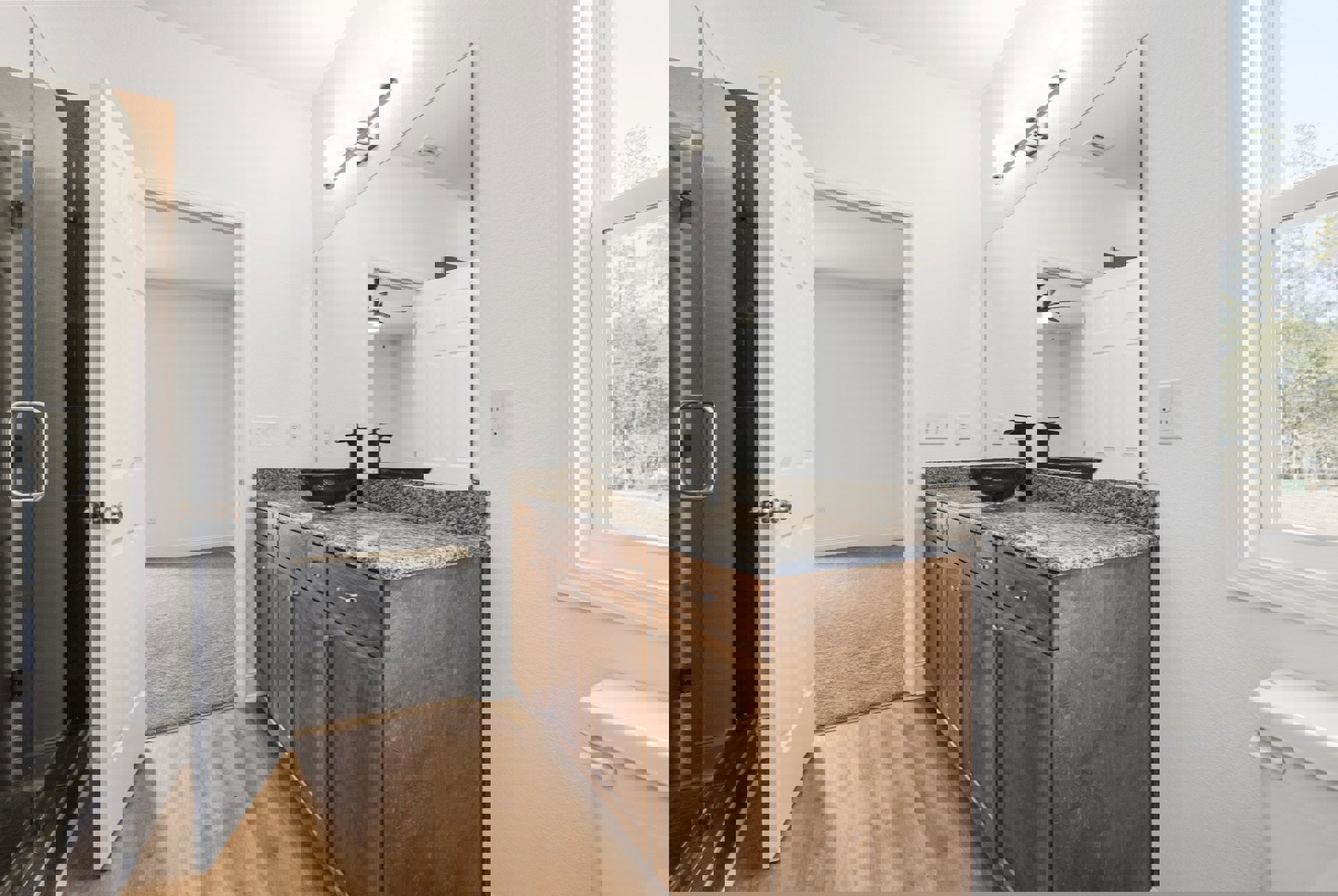 White quartz countertop with undermount sink, chrome faucet, rectangular wall mirror, light gray tile backsplash, white cabinetry, and electrical outlet visible on the wall