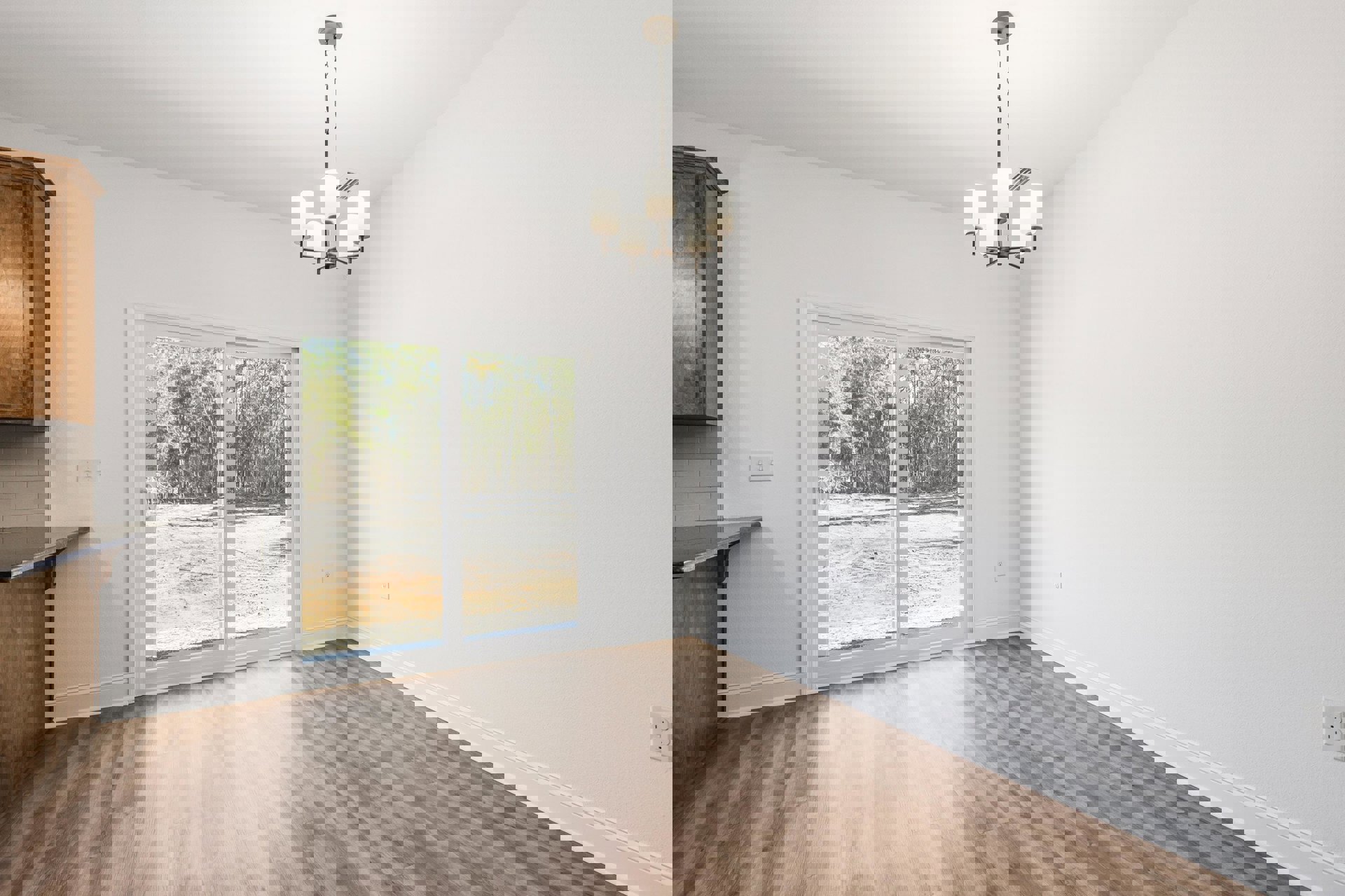 Wood flooring and plaster walls in a room featuring a wooden door, glass door, window overlooking forest, and chandelier with white lamps.