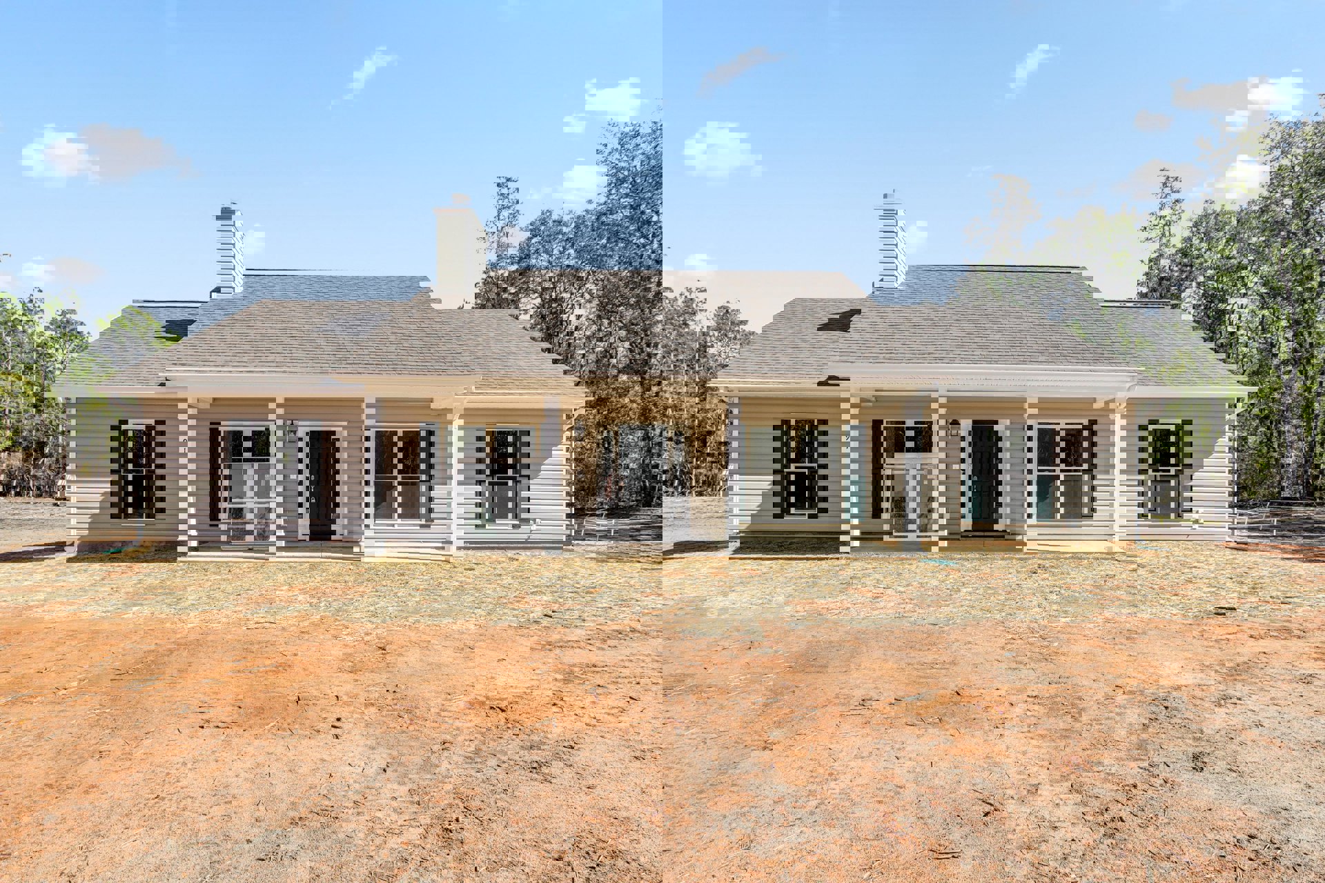Two-story house with black front door, white trim, covered porch, dirt yard, white-framed windows with black shutters, cloudy sky above