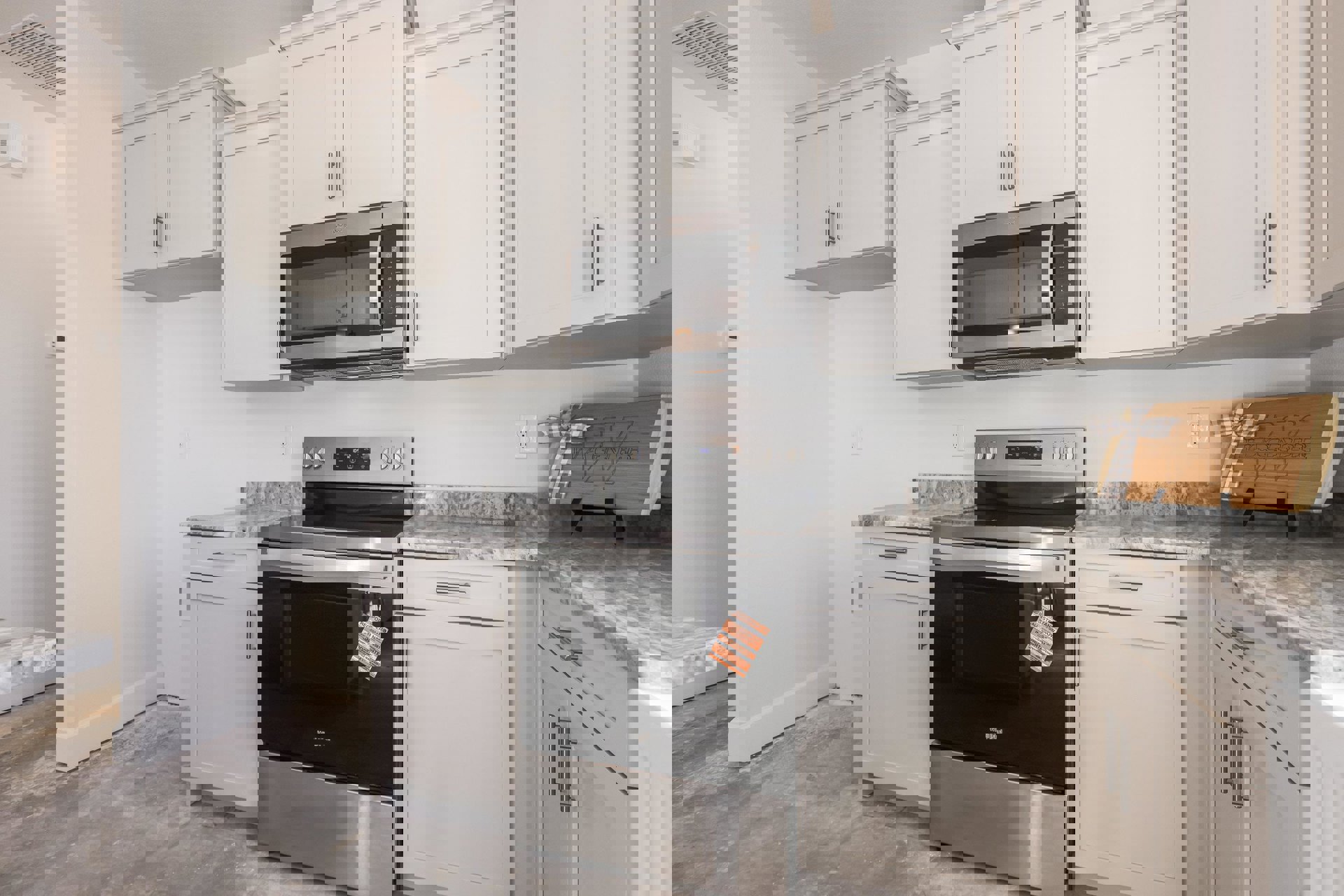 White shaker cabinets, stainless steel microwave oven above black and silver stove, quartz countertops, white tile backsplash, wood sign with bow on wall, white door with matching