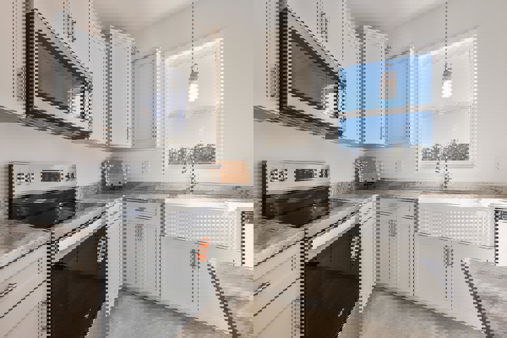 White shaker cabinets, marble countertop, stainless steel sink under window, built-in microwave, gas stove with oven, bright natural light