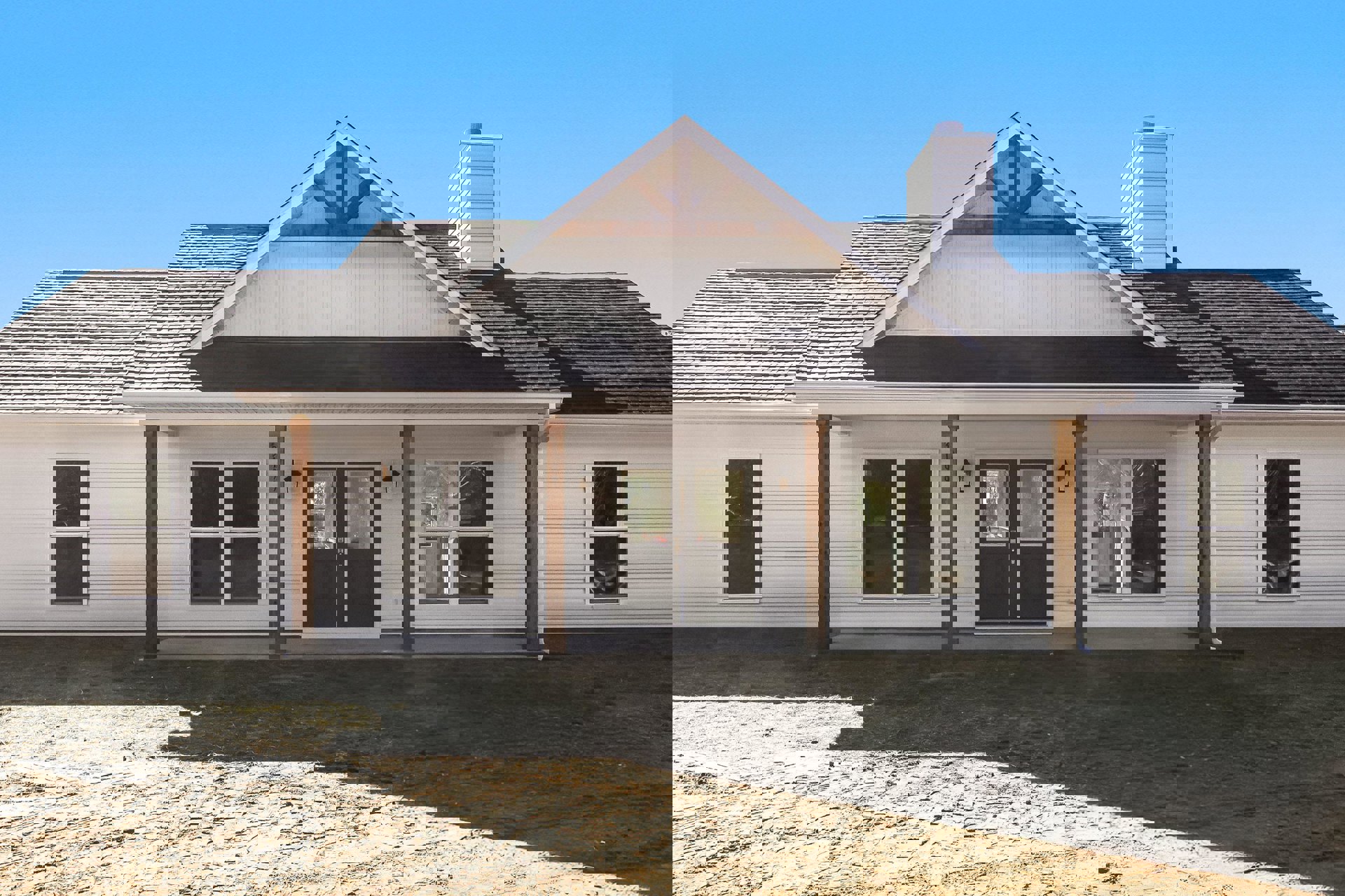 White siding house with brown shingle roof, double glass doors, multiple windows including one with visible spider web, dirt ground in front.