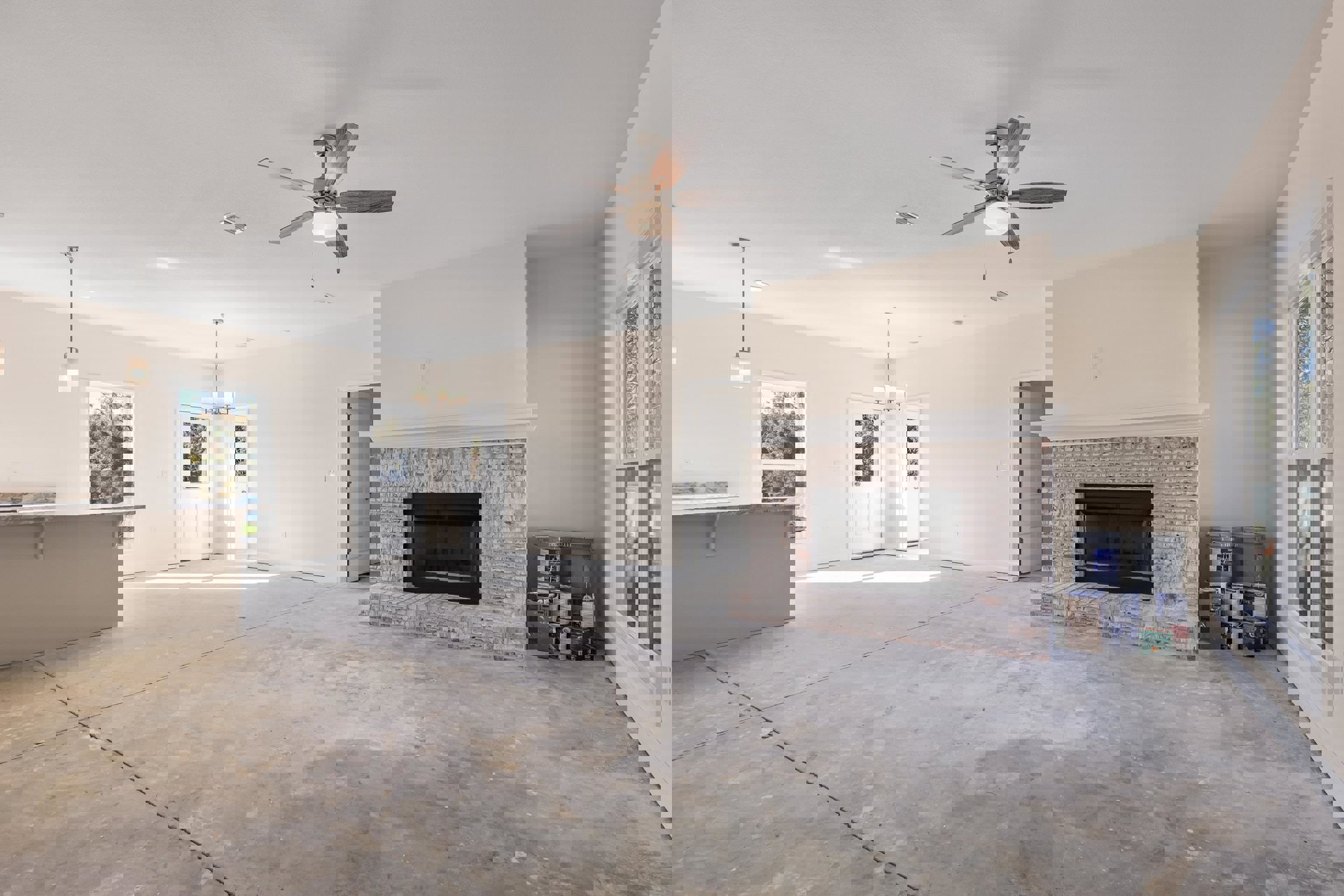 Living room featuring a brick fireplace, white door with window, ceiling fan with light, plaster walls, and large window overlooking trees.