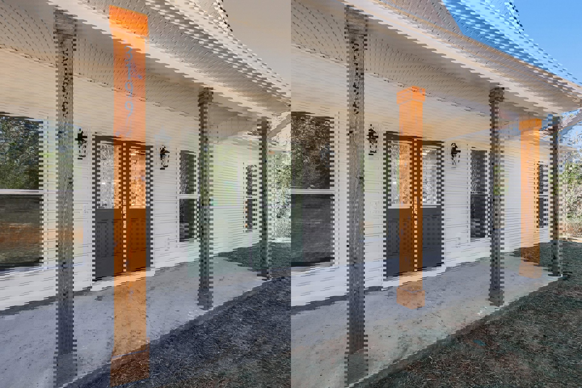 Front porch with green double doors featuring glass panes, wood plank flooring, wooden post with central hole, broken window glass, and metal lamp fixture.