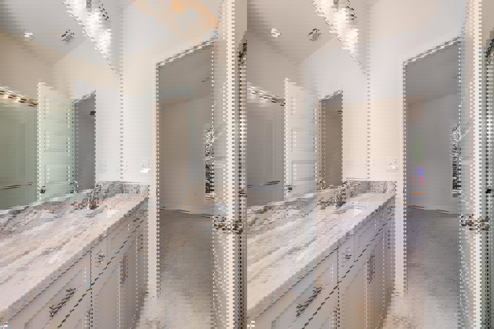 Bathroom featuring marble countertop, large frameless mirror, white cabinetry, chrome faucet, and tiled walls