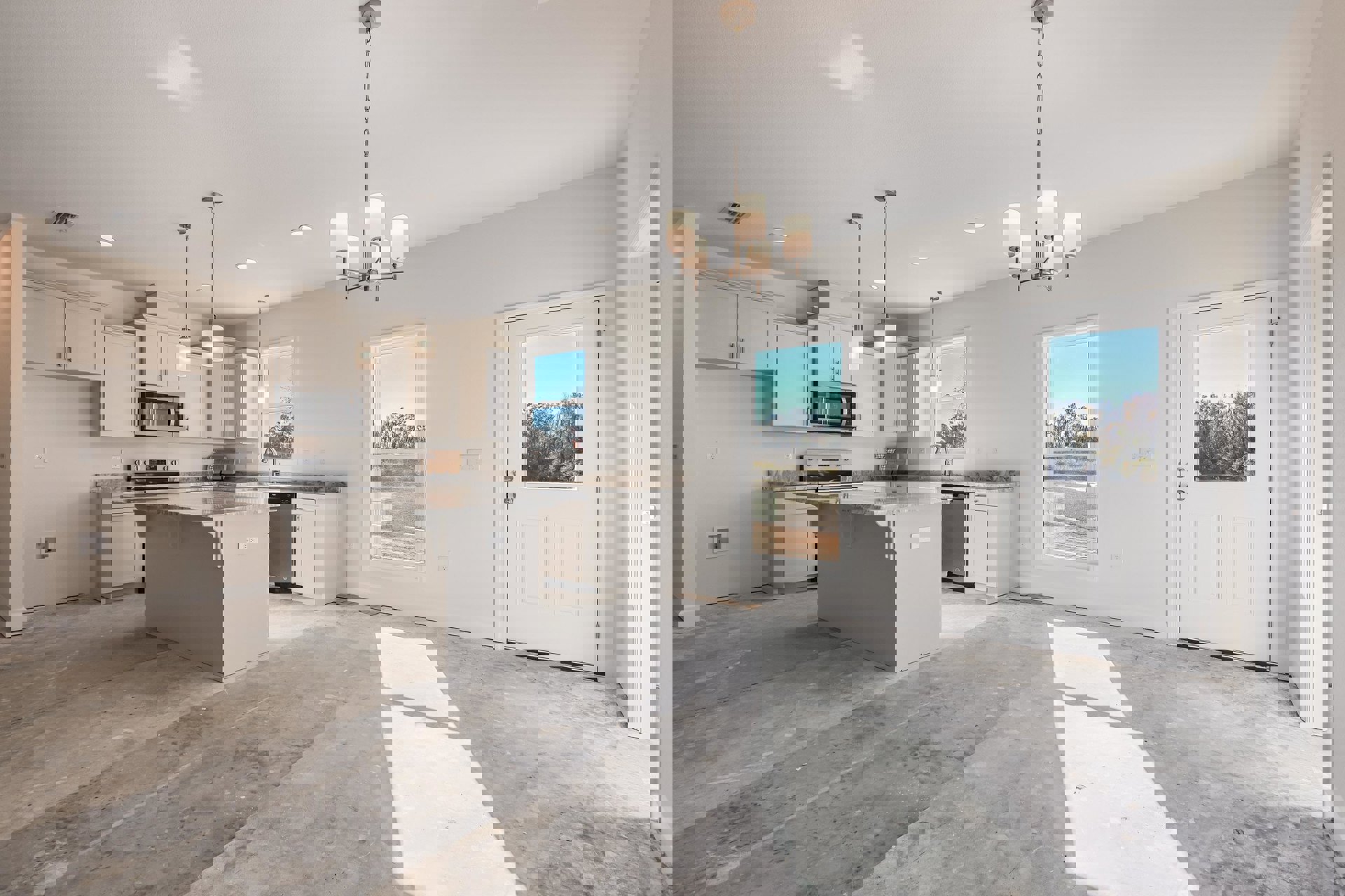 Kitchen with white cabinets and appliances, large marble-topped island, microwave with glass door, white door with window, and window overlooking trees.