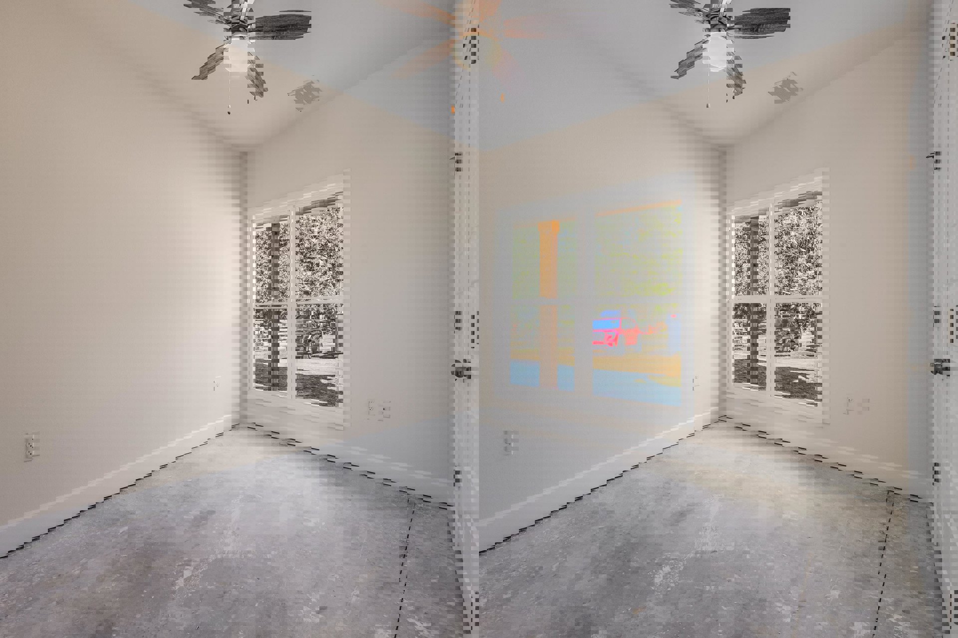 Ceiling fan with light fixture mounted on white ceiling, window with white trim overlooking red car parked outside, concrete floor, plaster walls, ceiling vent