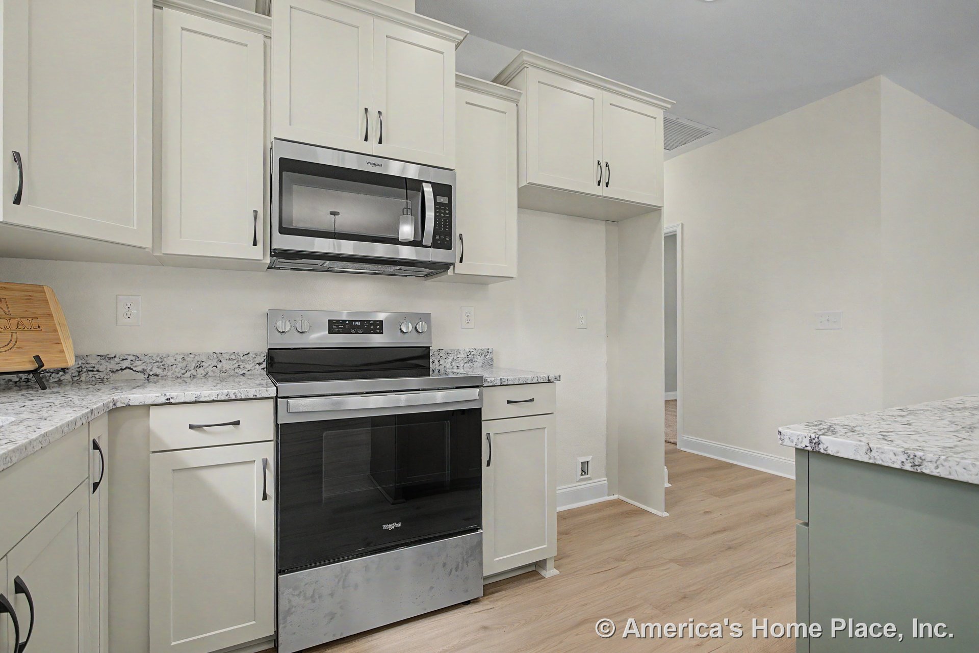 White shaker cabinetry with marble-look countertops, stainless steel range and microwave, light wood flooring, recessed ceiling lighting, and neutral wall paint.