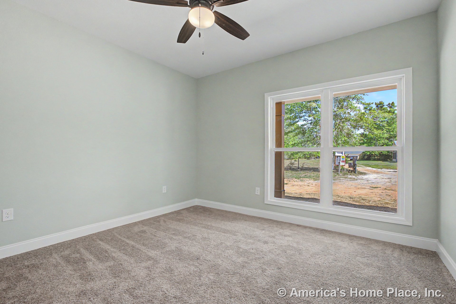 Bedroom with double window framed in white trim, light gray walls, carpet flooring, white baseboards, and ceiling fan with light fixture; natural light fills the empty space.