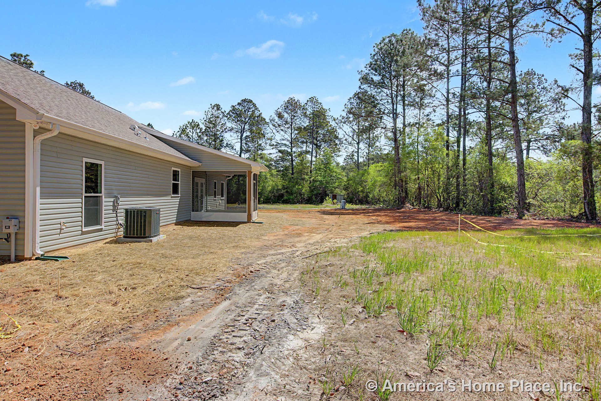 Gray vinyl siding exterior with multiple rectangular windows, sloped shingle roof, covered rear porch, white gutters and downspouts, and backyard HVAC unit.