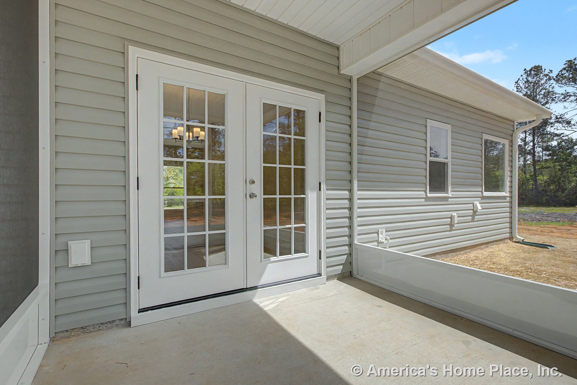 Covered patio with double French doors featuring glass panes, light gray vinyl siding, concrete flooring, exterior windows, and a finished ceiling.