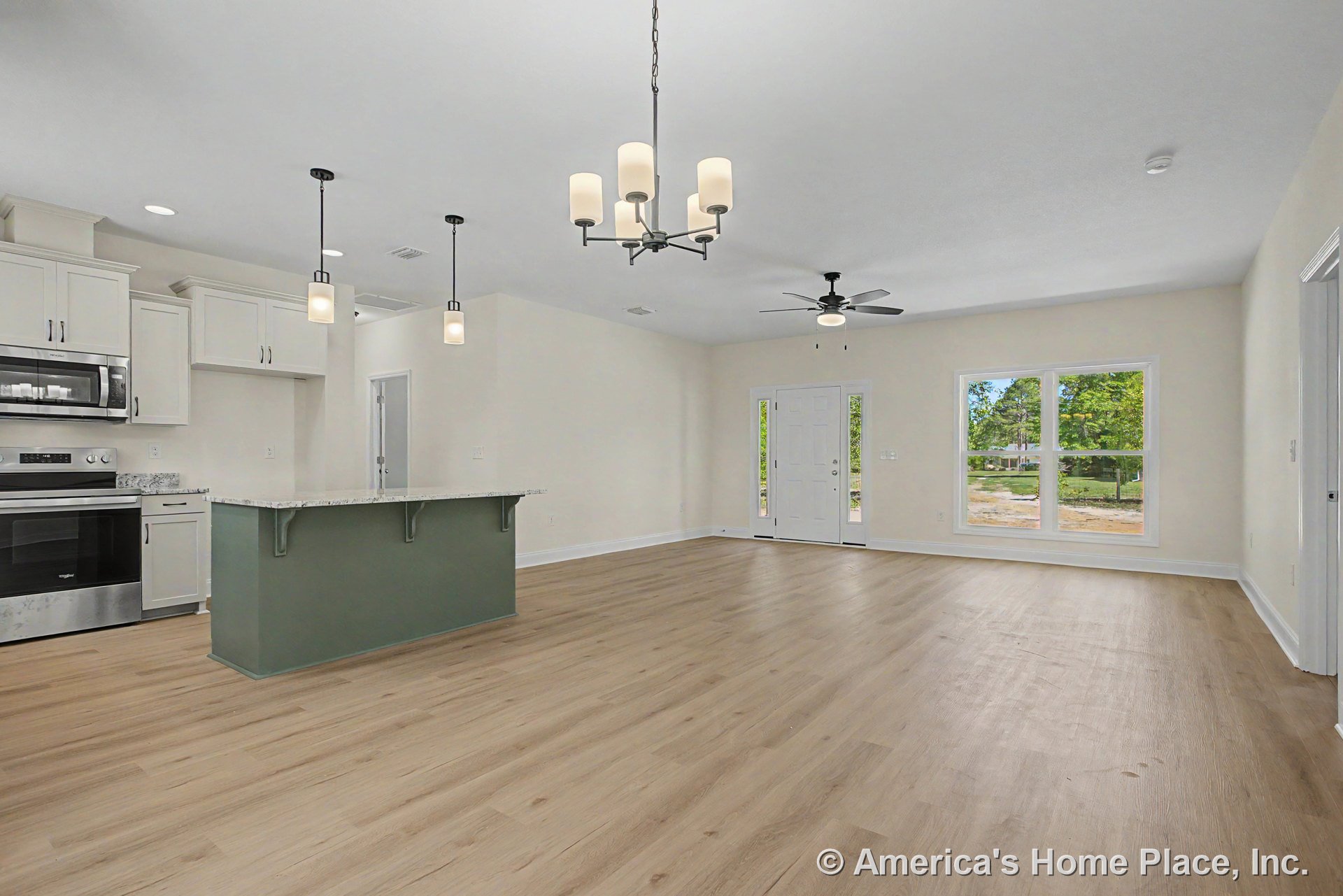 Open-concept living area with light wood flooring, large window wall, kitchen island featuring granite countertops and white shaker cabinetry, stainless appliances, pendant and