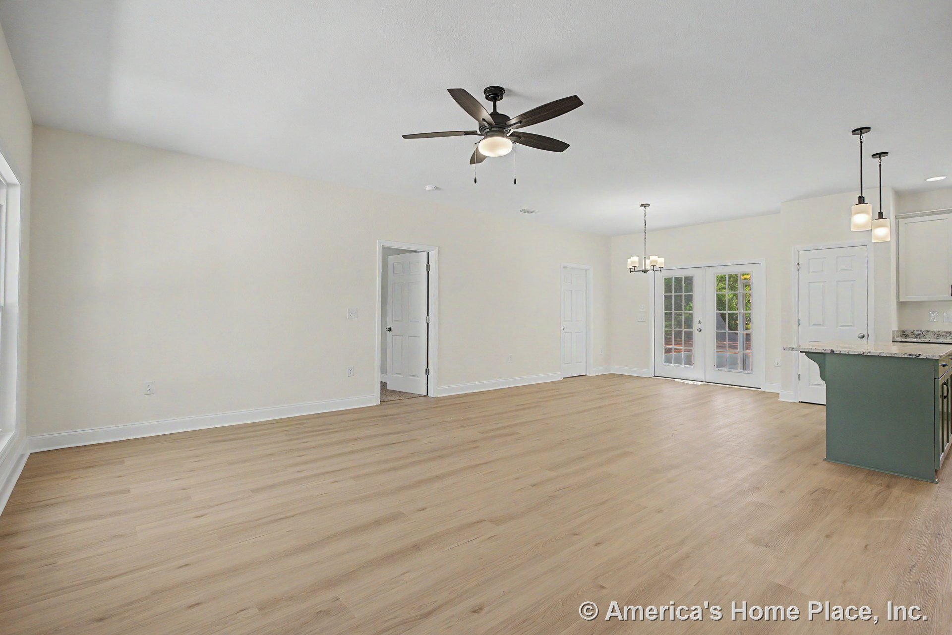 Open concept living area with light wood plank flooring, ceiling fan with integrated light, pendant and chandelier fixtures, white trim and doors, French doors leading to patio
