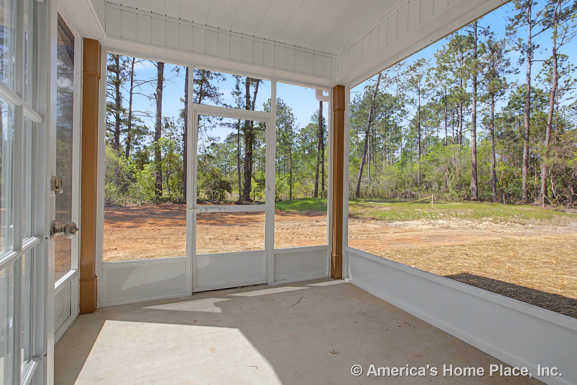 Screened porch with concrete flooring, white ceiling panels, glass door featuring metal hardware, and white-trimmed windows overlooking wooded outdoor scenery.