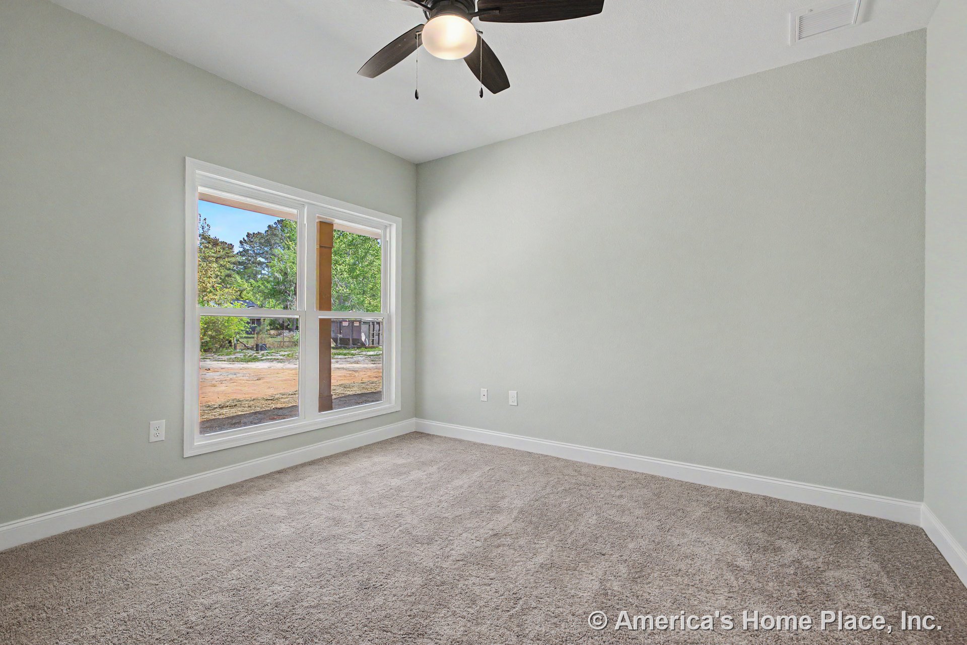 Large double window with white trim allows natural light into bedroom with neutral carpet flooring, light gray painted walls, white baseboards, ceiling fan with integrated light