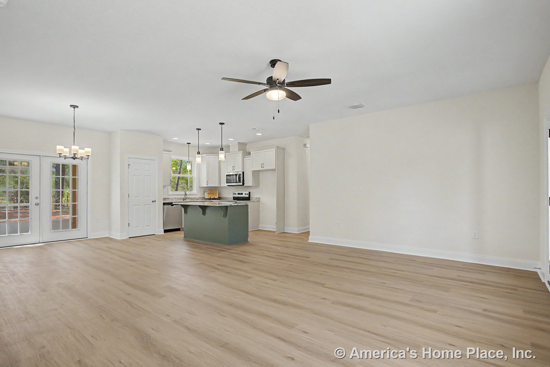 Open-concept living area with light wood plank flooring, white shaker kitchen cabinets, granite countertops, kitchen island, stainless appliances, pendant and recessed lighting