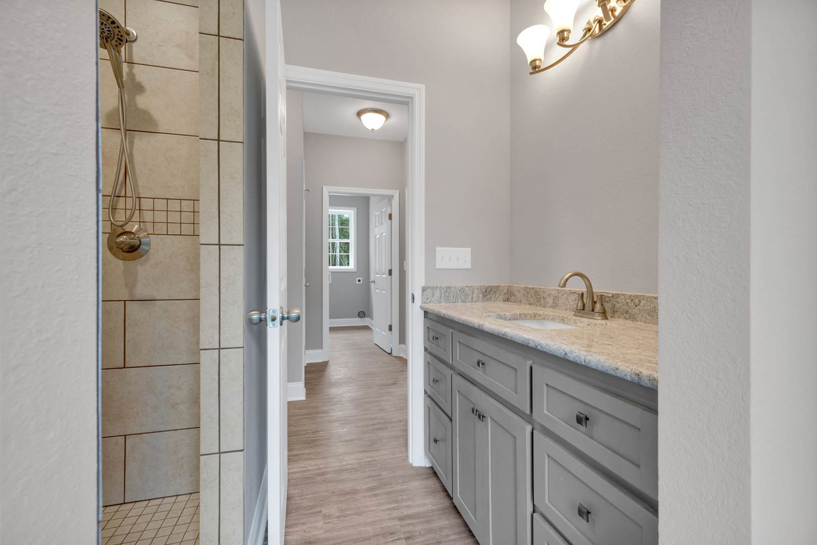 Bathroom featuring a marble countertop, wood flooring, white cabinetry, ceiling light fixture, window with white frame, and a shower head.