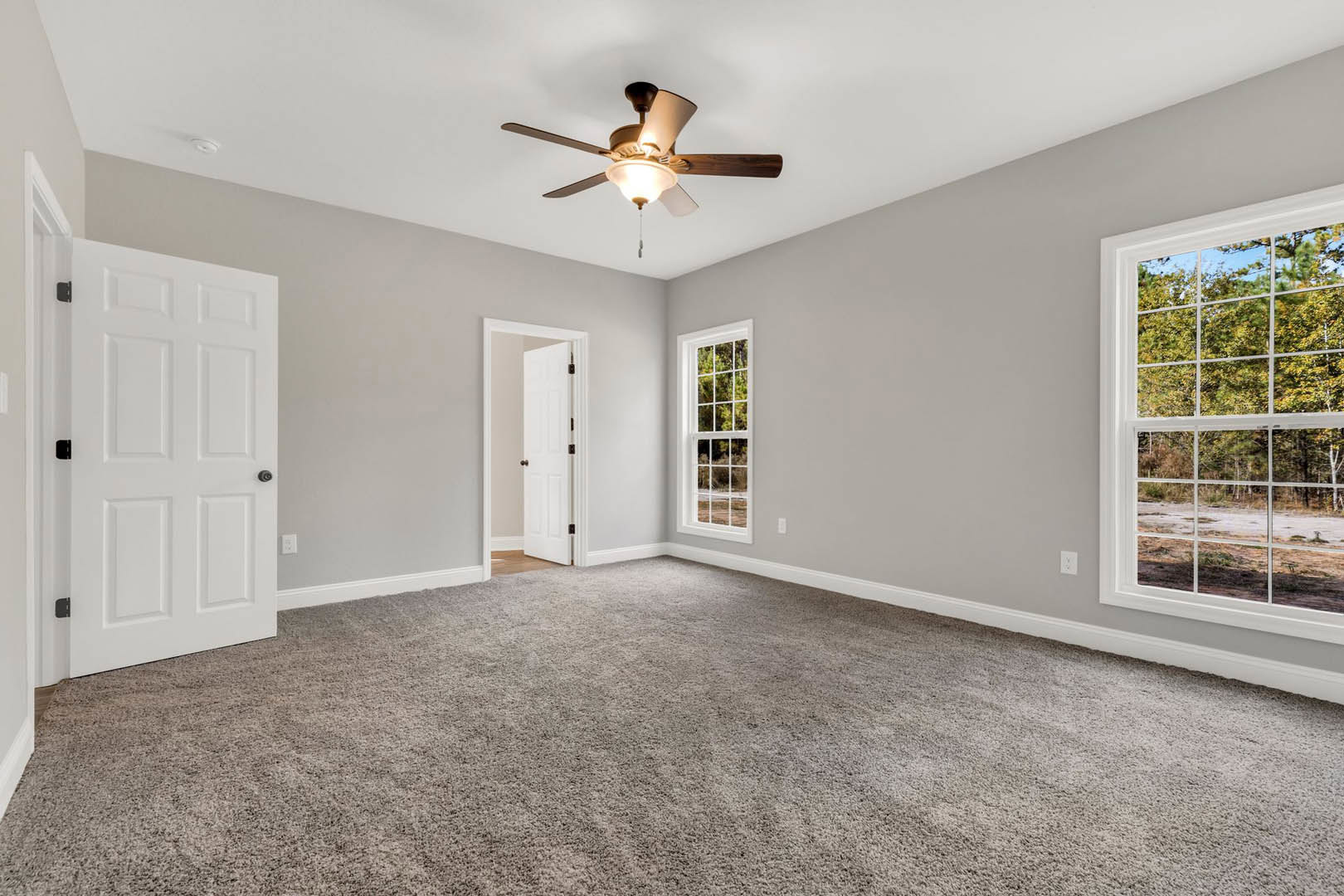 Ceiling fan with light fixture, multiple-paned windows, white door with black knobs, carpeted floor, neutral walls
