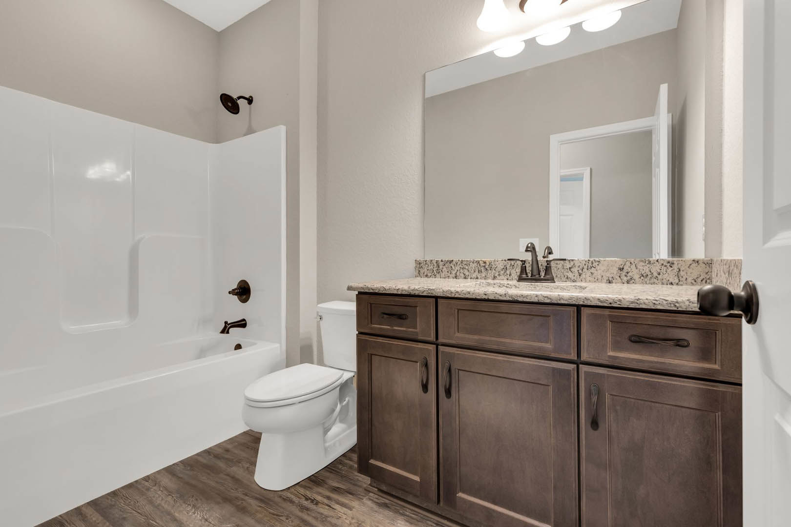 White bathroom featuring a wall-mounted sink, closed toilet, glass-enclosed shower with chrome fixtures, white tile walls, and a white door with a visible light switch.