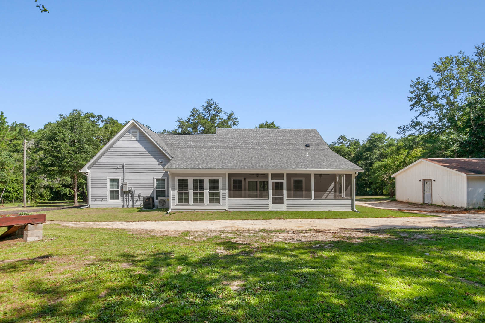 Two-story house with white siding, covered front porch, manicured lawn, mature trees, and Robert Frost Farm visible in the background.