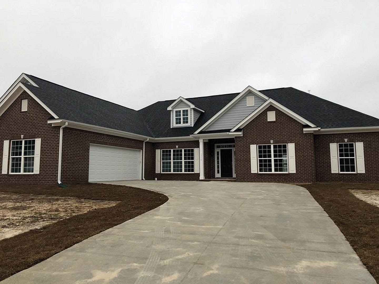 Red brick house with white garage door, paved driveway, white-framed window, and white entry door