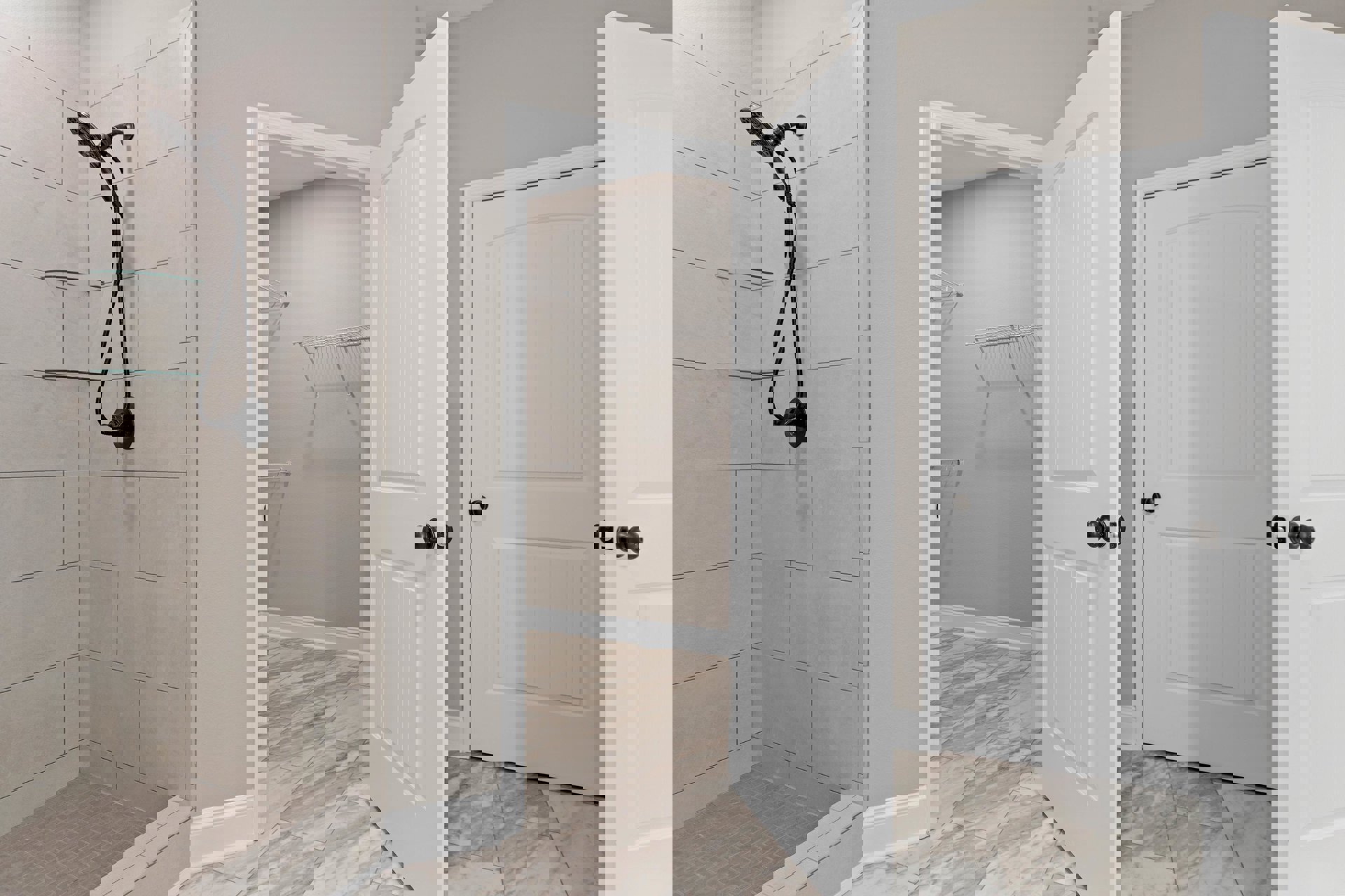 Bathroom with white tile floor, open white door with black knobs, shower head with hose, and closet with built-in shelves