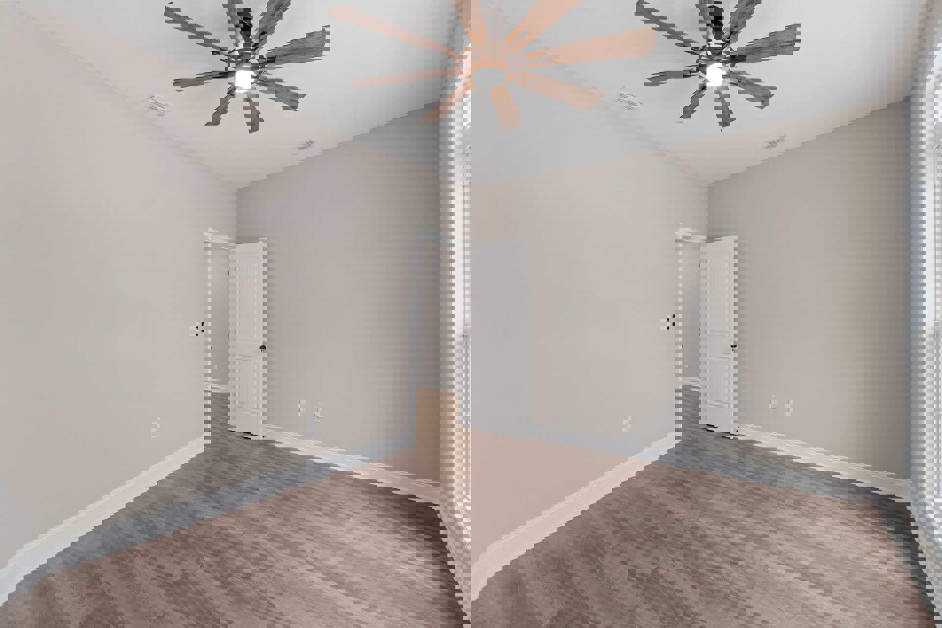 Ceiling fan with integrated light fixture, wood flooring, white door with black knob, white walls with crown molding