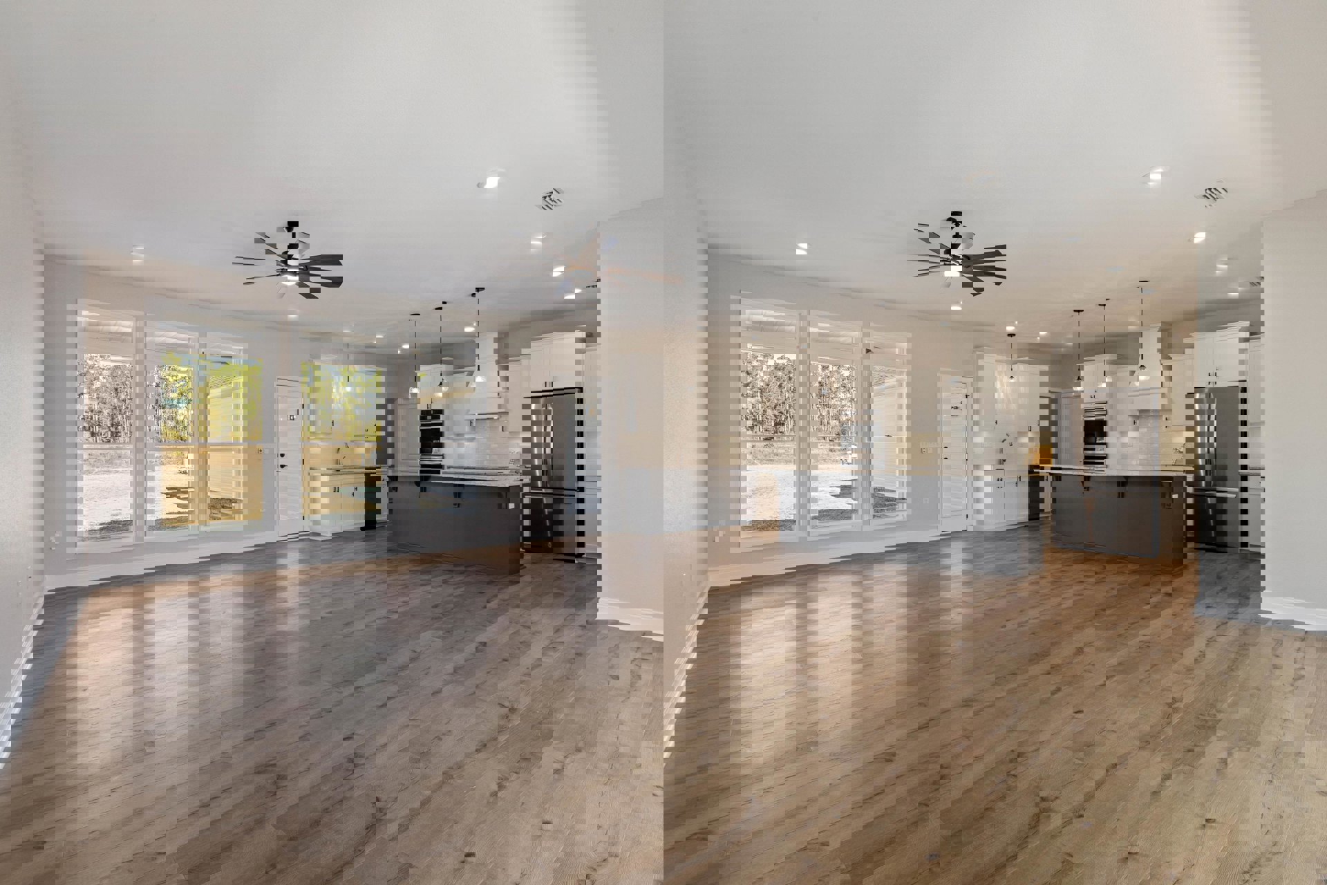 Open-concept kitchen and dining area with white cabinets, stainless steel appliances, wood flooring, ceiling fan with light, and white door featuring a black handle