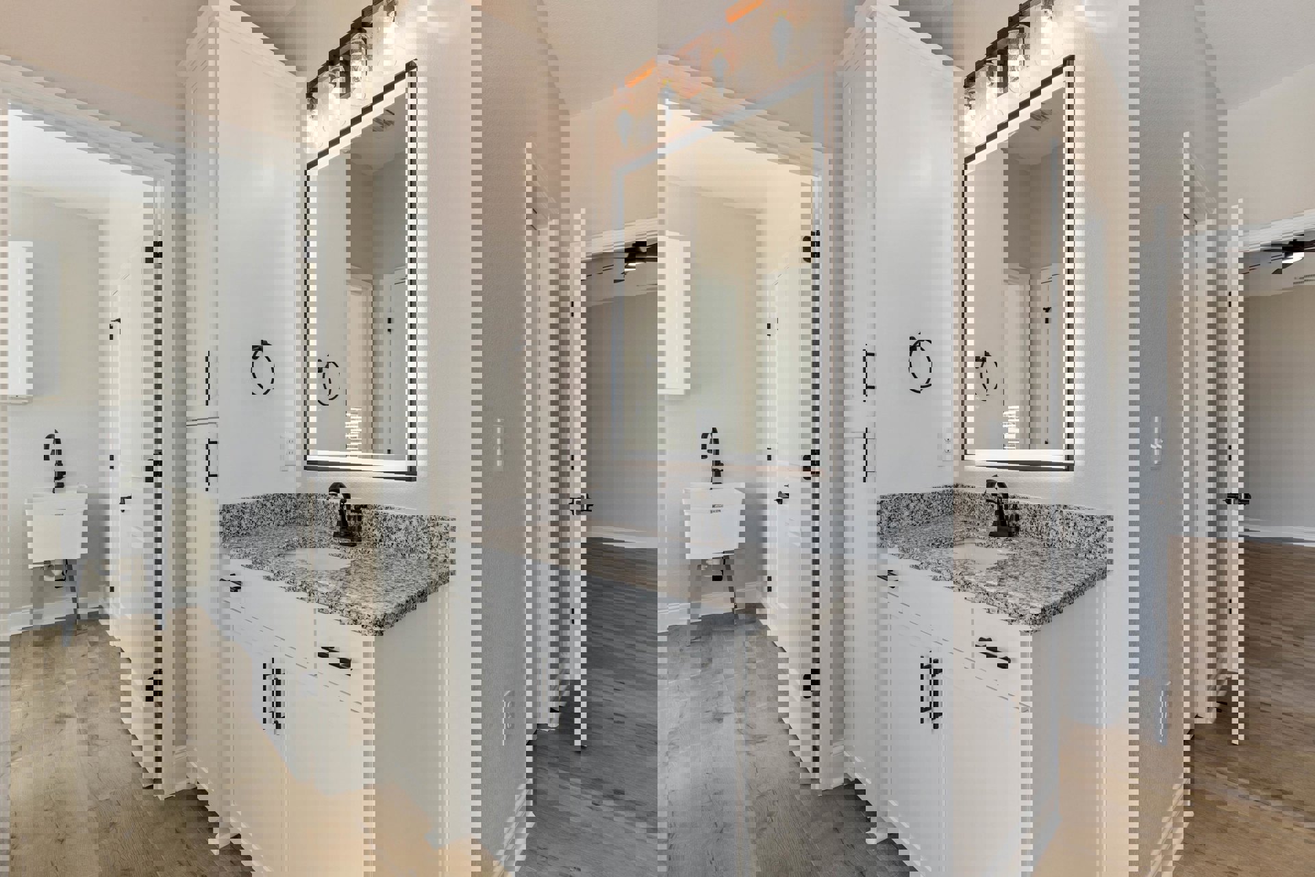 Marble bathroom countertop with white sink and black faucet, rectangular mirror above, black towel ring mounted on white wall, single exposed bulb light fixture.