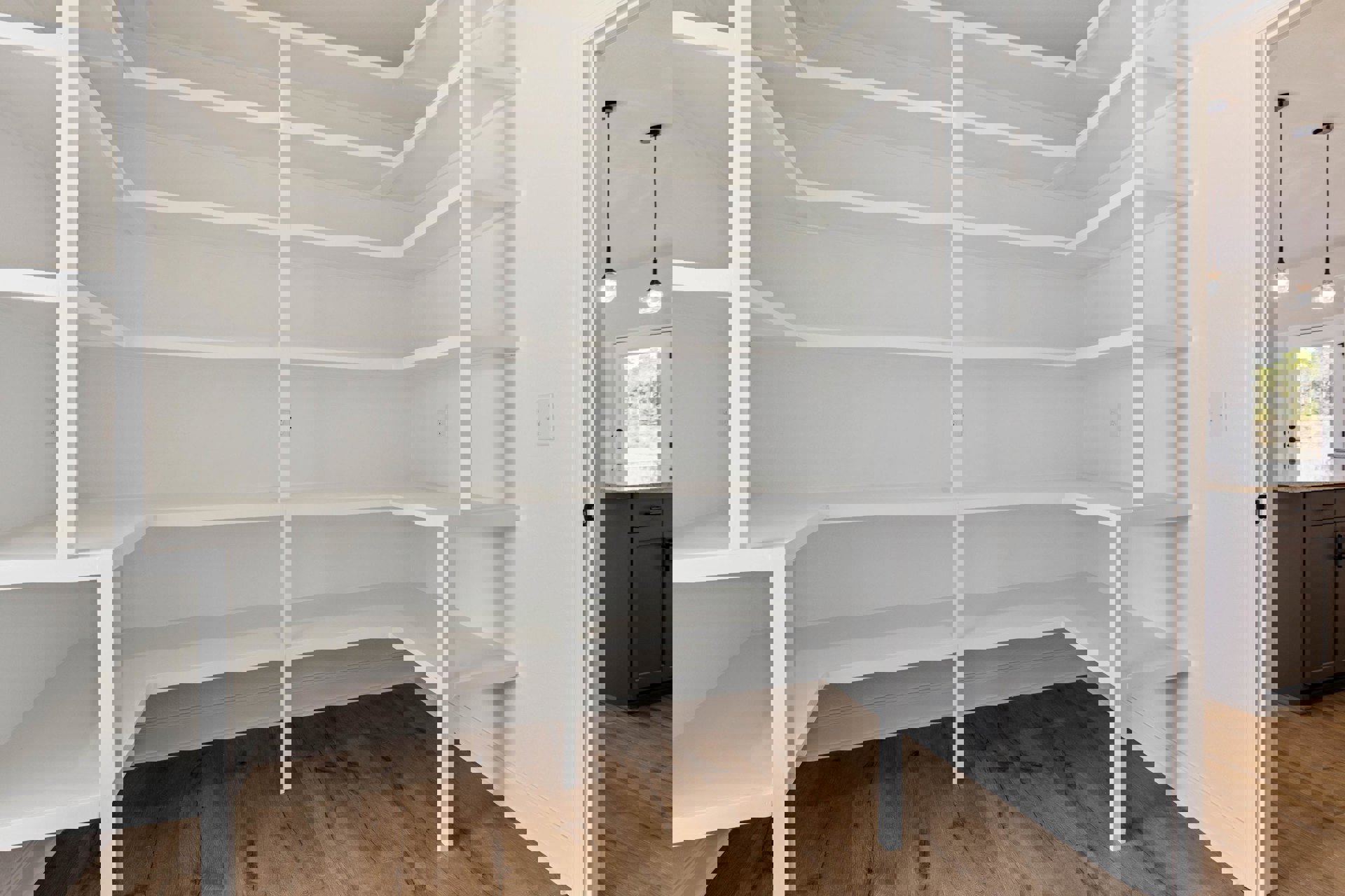 White built-in shelves against a light wall, clear glass pendant light overhead, black wire resting on white countertop, white door with window panel, close-up of door detailing