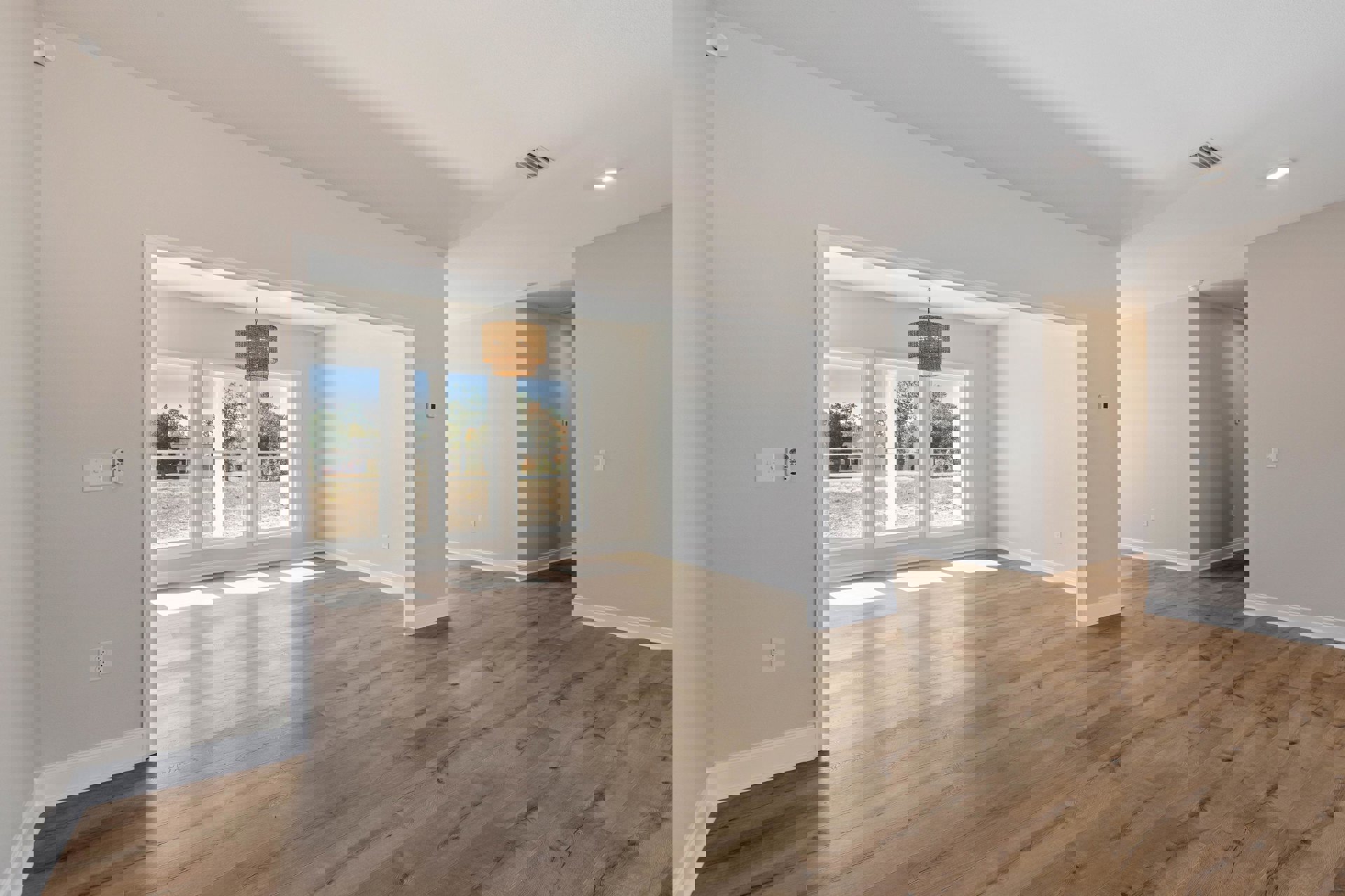 Wood flooring in a room with white walls, white ceiling, woven pendant light fixture, and large windows
