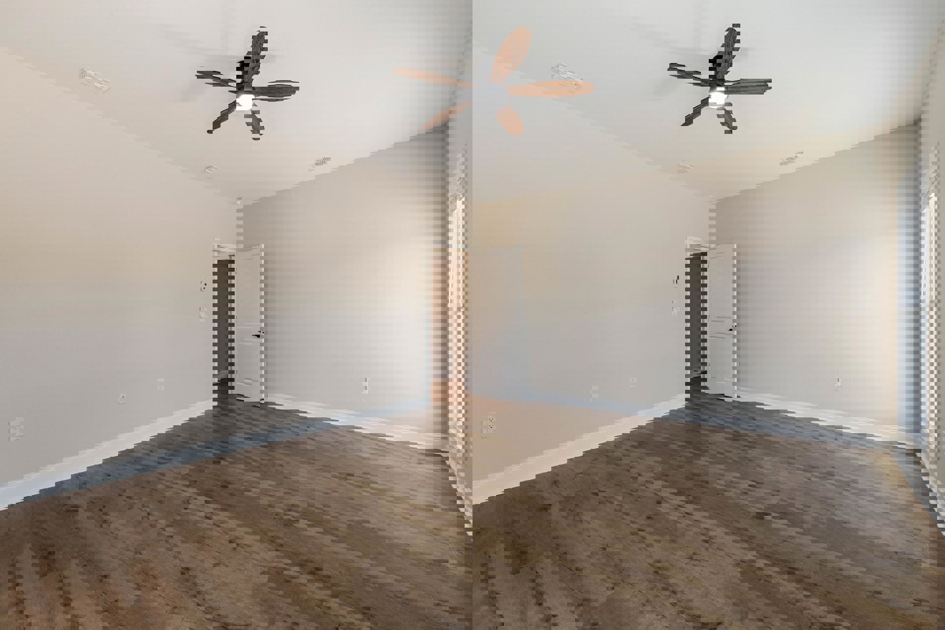 Ceiling fan with light fixture, wood plank flooring, white door with black handle, brown accent wall with white trim, window with white frame