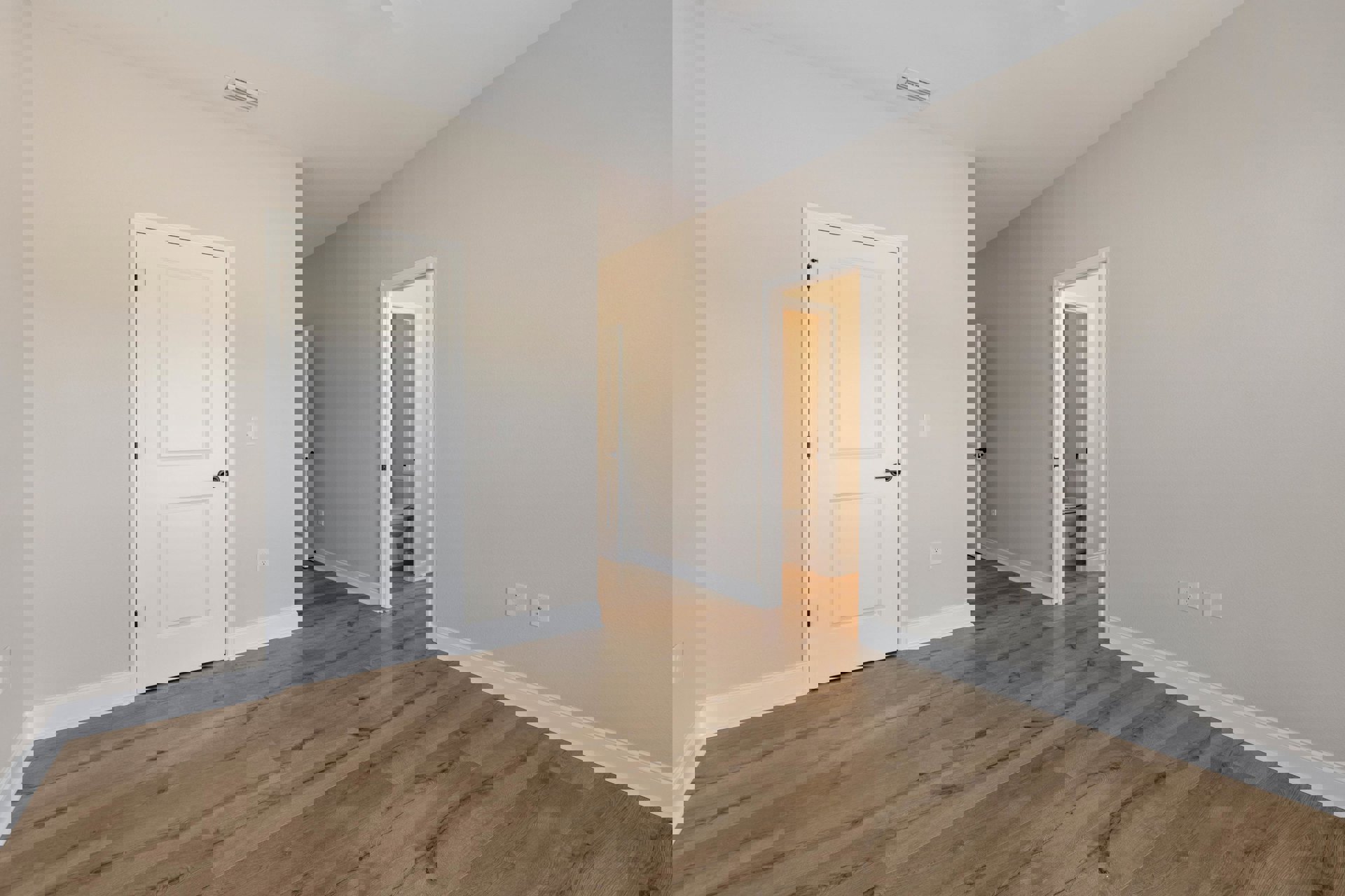 Hardwood floor room with white walls, white door featuring black handle, and adjacent bathroom with visible toilet