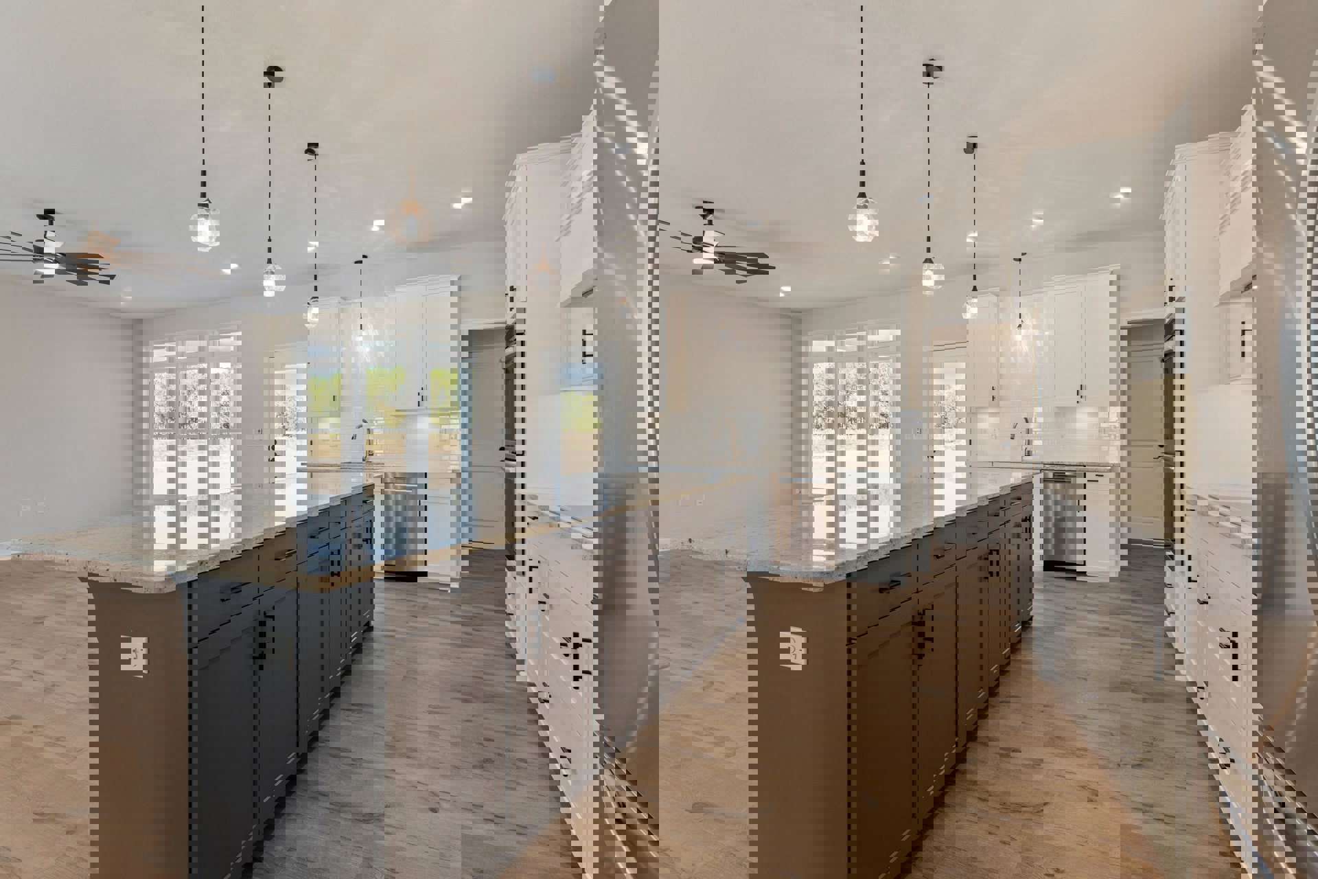 Spacious kitchen featuring a large central island with white countertop, wood flooring, white cabinetry, stainless steel dishwasher, and wall outlet visible near the island