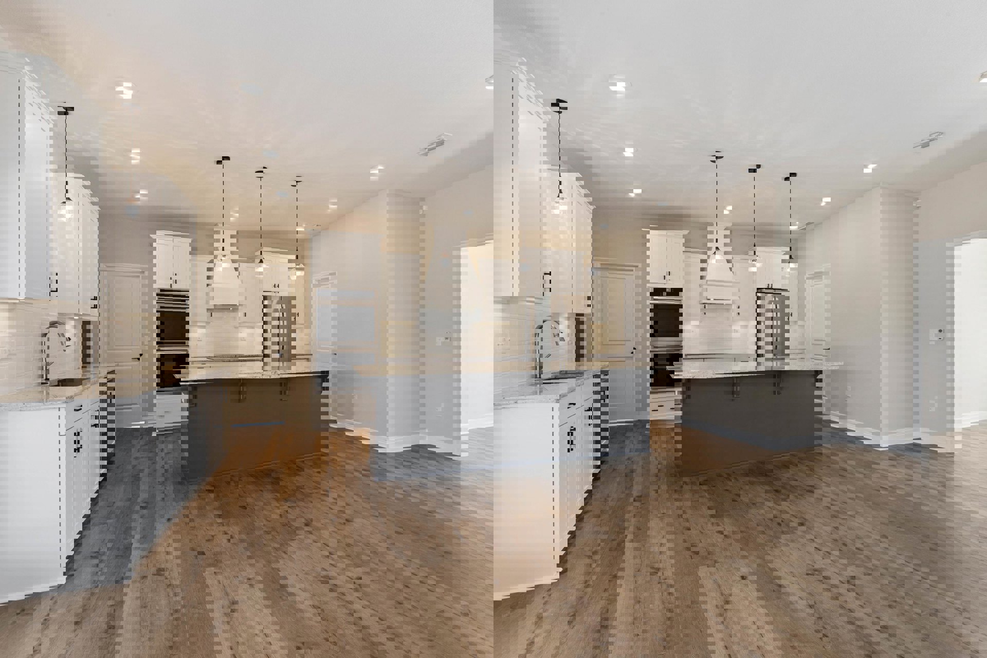 Spacious kitchen featuring a large central island with stone countertop, wood flooring, grey walls, stainless steel refrigerator and microwave, white cabinetry, and undermount